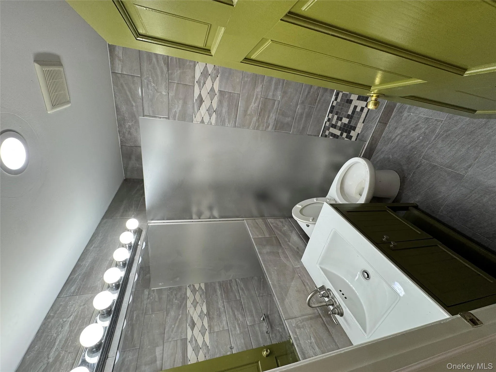 Full bath featuring vanity, walk in shower, tile walls, and dark tile patterned flooring Full bath featuring vanity, walk in shower, tile walls, and dark tile patterned flooring