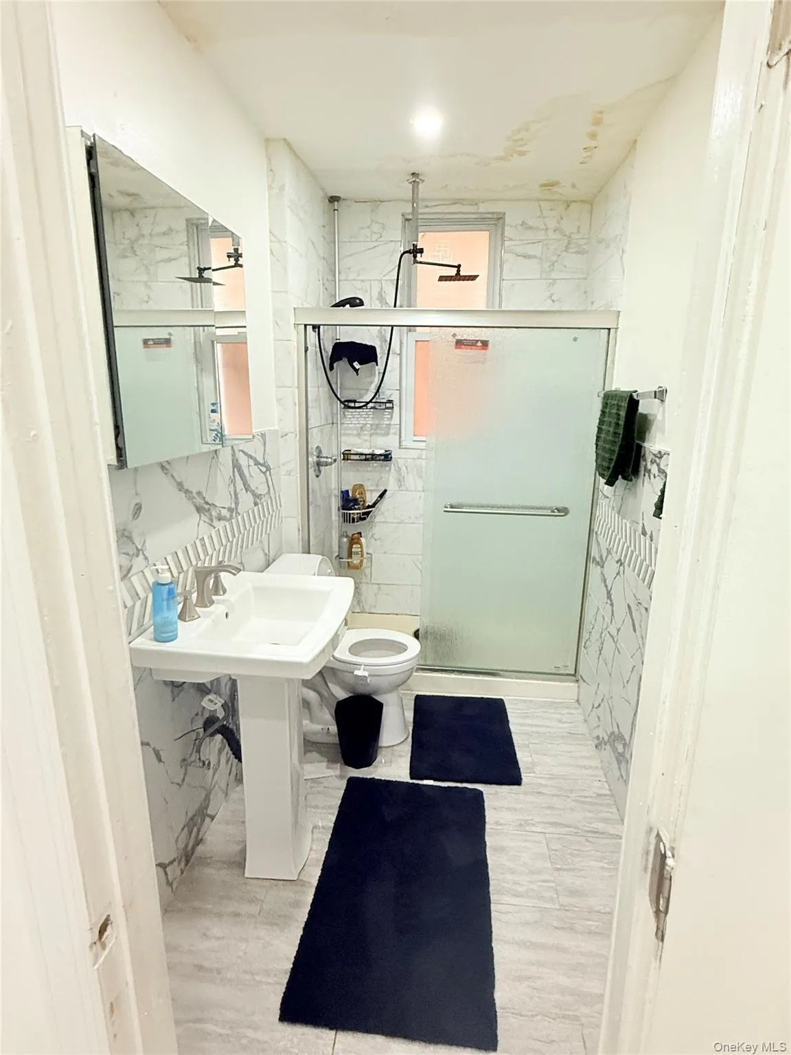 Bathroom featuring a marble finish shower and tile walls Bathroom featuring a marble finish shower and tile walls