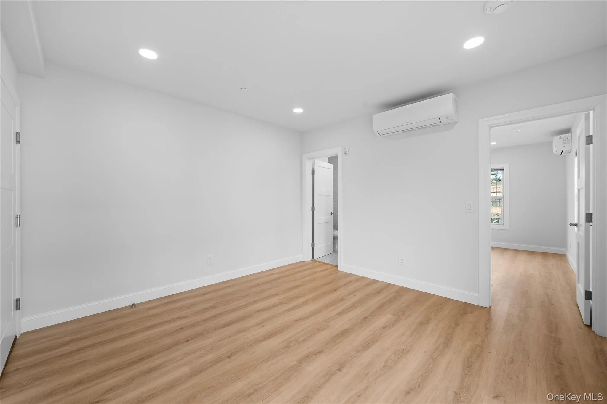 Unfurnished bedroom featuring recessed lighting, a wall mounted air conditioner, and light wood-type flooring Unfurnished bedroom featuring recessed lighting, a wall mounted air conditioner, and light wood-type flooring