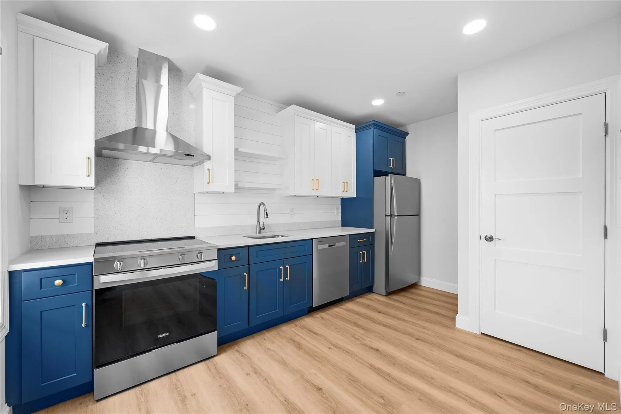 Kitchen with stainless steel appliances, blue cabinetry, wall chimney exhaust hood, white cabinetry, and decorative backsplash Kitchen with stainless steel appliances, blue cabinetry, wall chimney exhaust hood, white cabinetry, and decorative backsplash