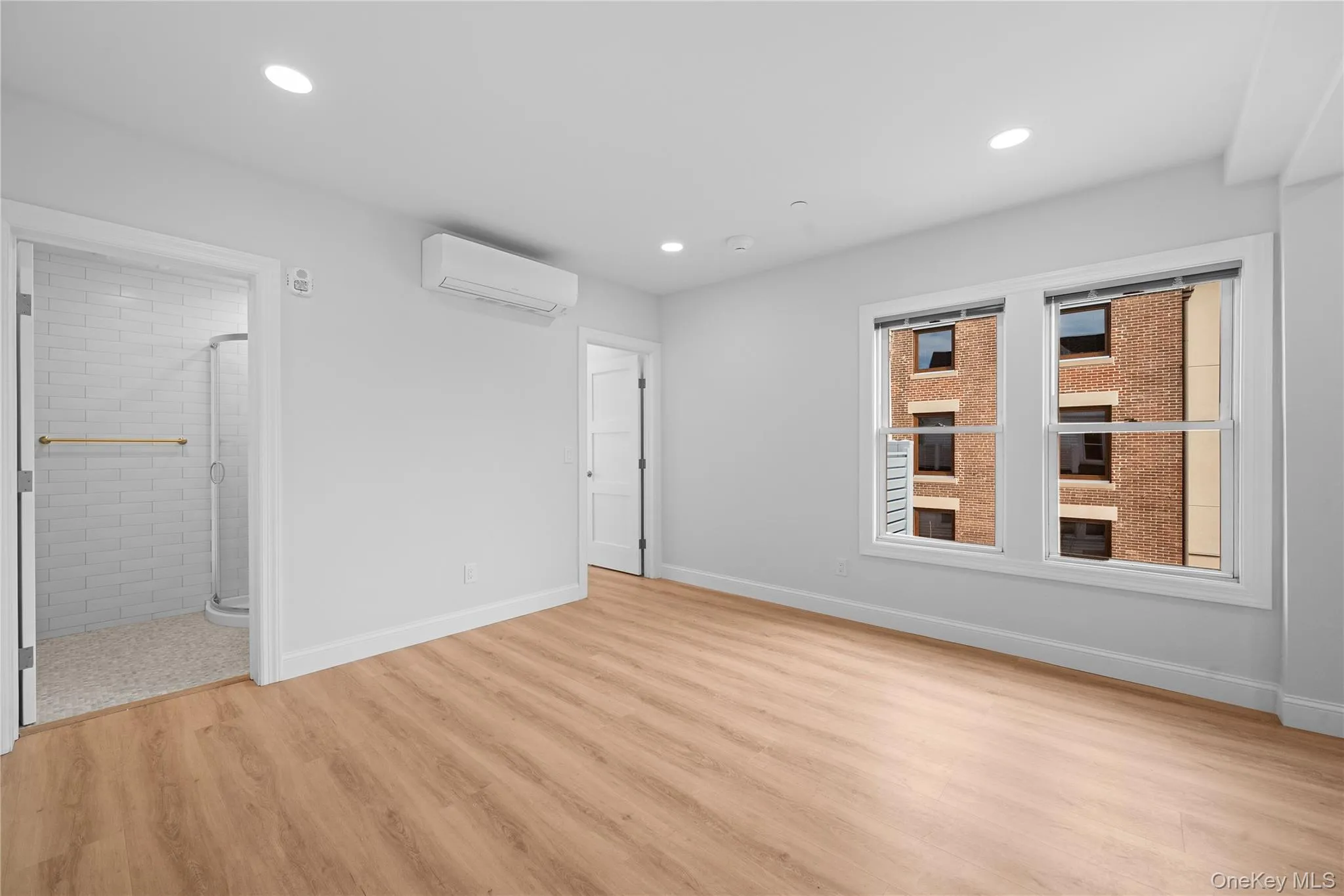 Unfurnished bedroom featuring light wood-type flooring, an AC wall unit, recessed lighting, and connected bathroom Unfurnished bedroom featuring light wood-type flooring, an AC wall unit, recessed lighting, and connected bathroom