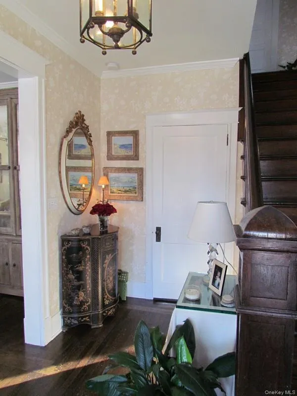 Foyer entrance with a chandelier, dark hardwood / wood-style flooring, and ornamental molding Foyer entrance with a chandelier, dark hardwood / wood-style flooring, and ornamental molding