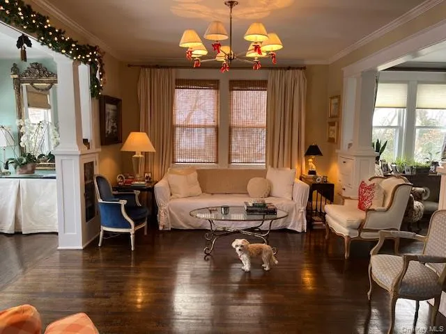Living area with dark hardwood / wood-style flooring, crown molding, and decorative columns Living area with dark hardwood / wood-style flooring, crown molding, and decorative columns