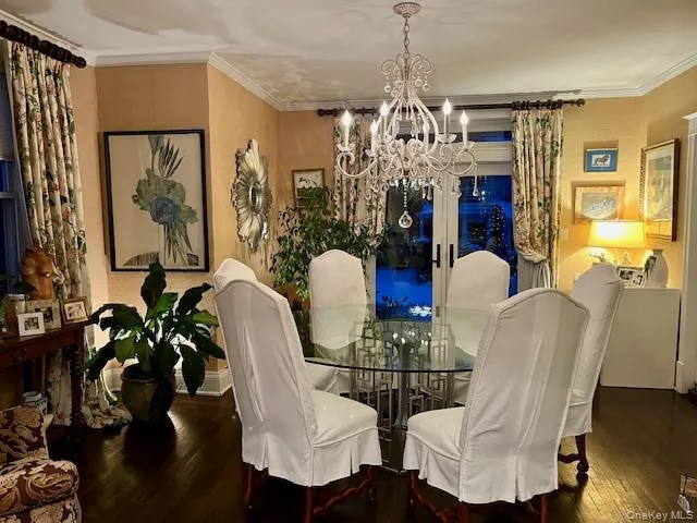 Dining space with hardwood / wood-style flooring, ornamental molding, and a chandelier Dining space with hardwood / wood-style flooring, ornamental molding, and a chandelier
