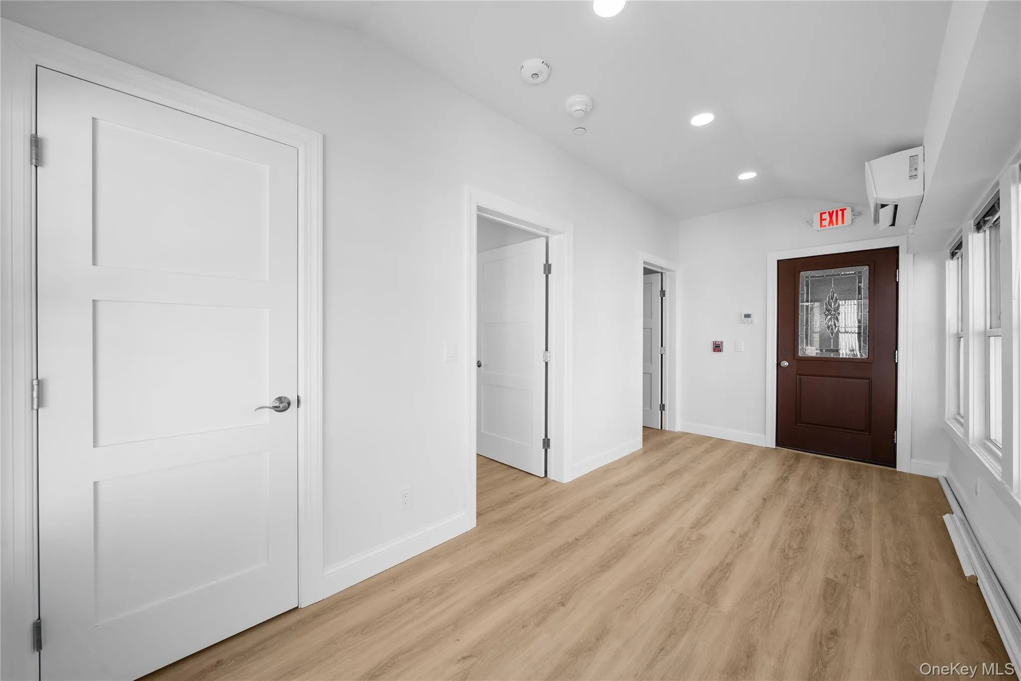 Foyer with a baseboard radiator, lofted ceiling, recessed lighting, light wood-style floors, and a wall mounted air conditioner Foyer with a baseboard radiator, lofted ceiling, recessed lighting, light wood-style floors, and a wall mounted air conditioner