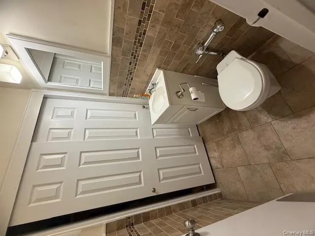 Bathroom with tile walls, vanity, wainscoting, and light tile patterned flooring Bathroom with tile walls, vanity, wainscoting, and light tile patterned flooring