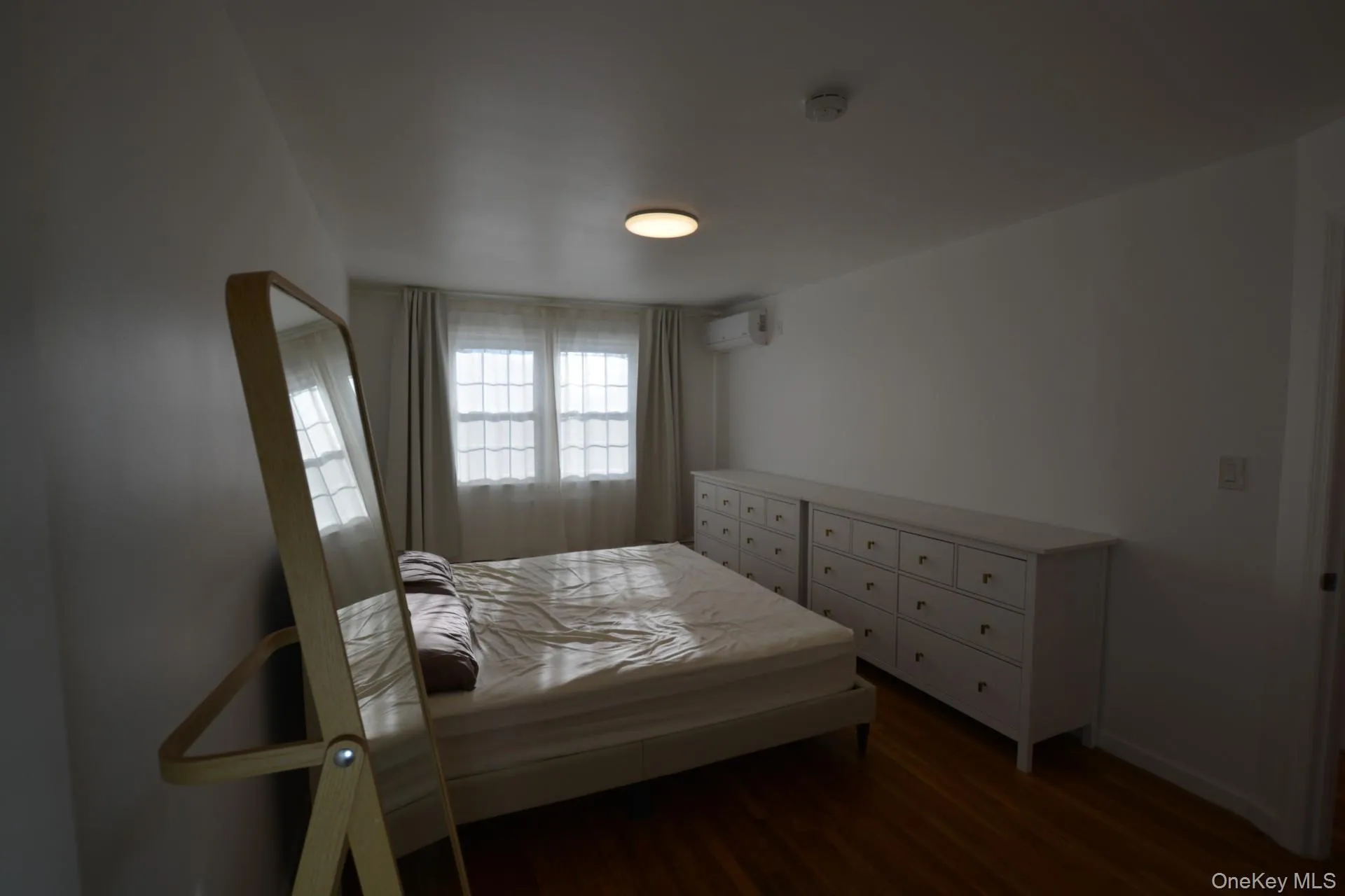 Bedroom featuring dark wood-style flooring and a wall unit AC Bedroom featuring dark wood-style flooring and a wall unit AC