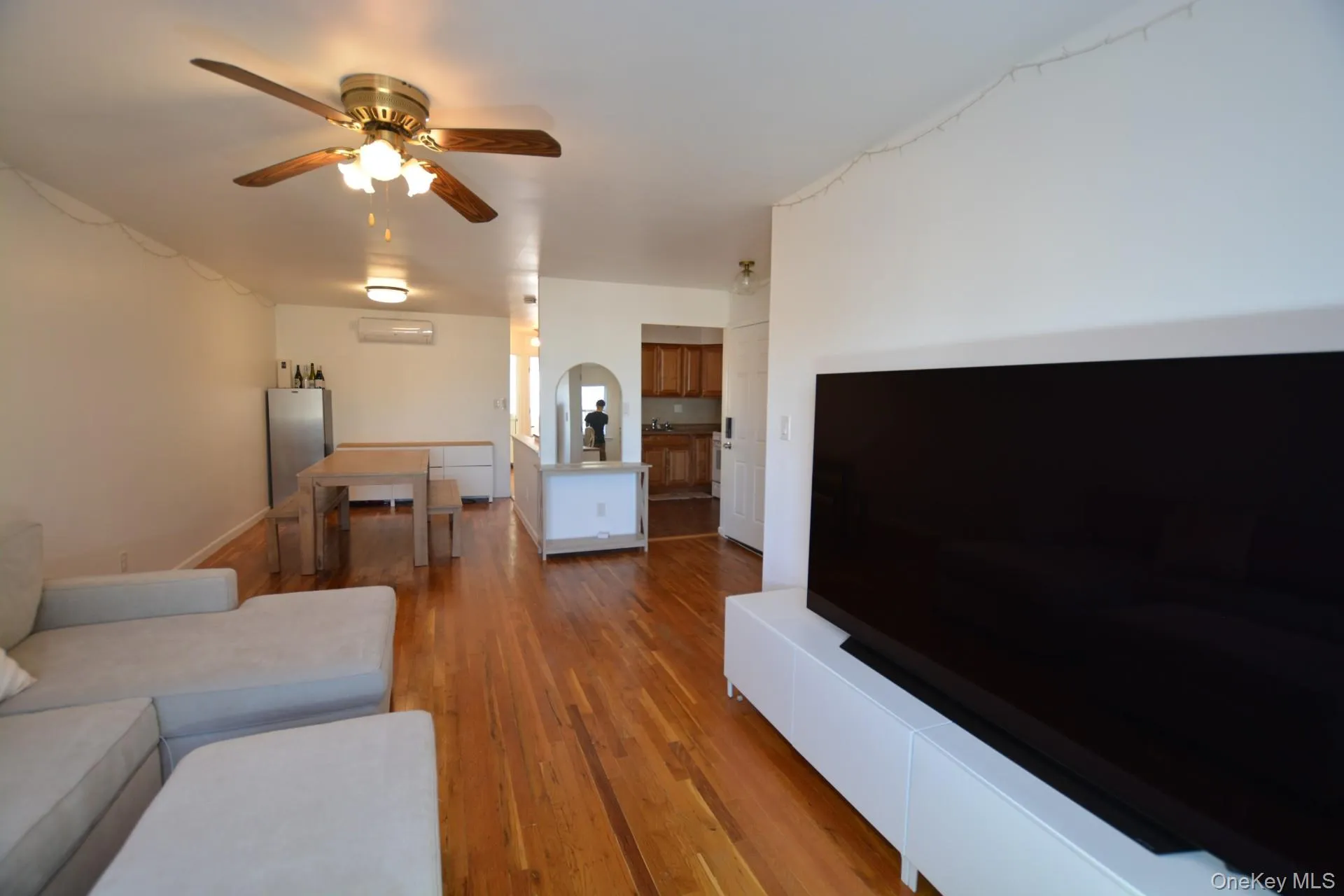 Living room with hardwood / wood-style flooring, a ceiling fan, and a wall mounted AC Living room with hardwood / wood-style flooring, a ceiling fan, and a wall mounted AC