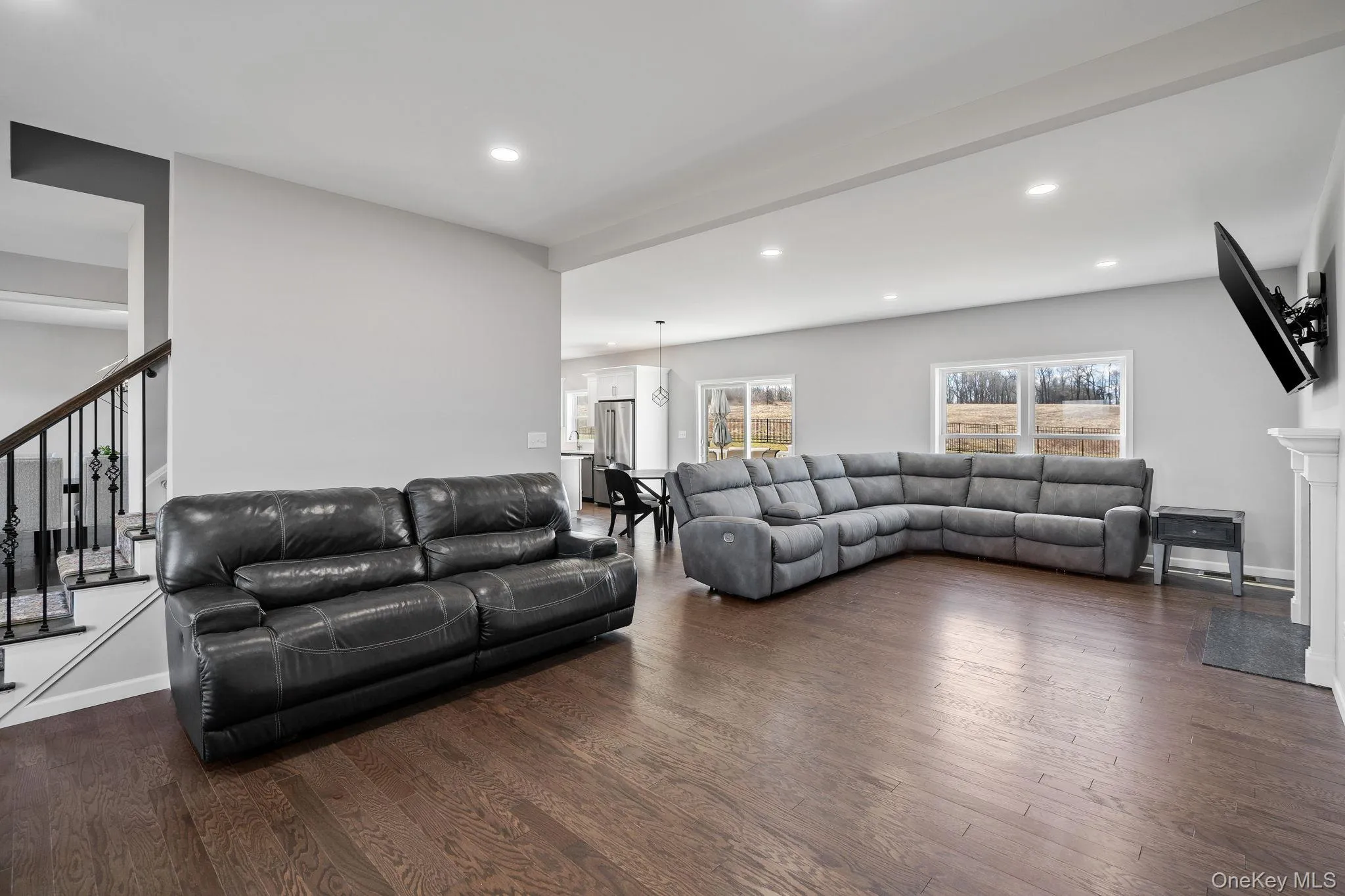 Living room with dark wood-type flooring, stairway, and recessed lighting Living room with dark wood-type flooring, stairway, and recessed lighting