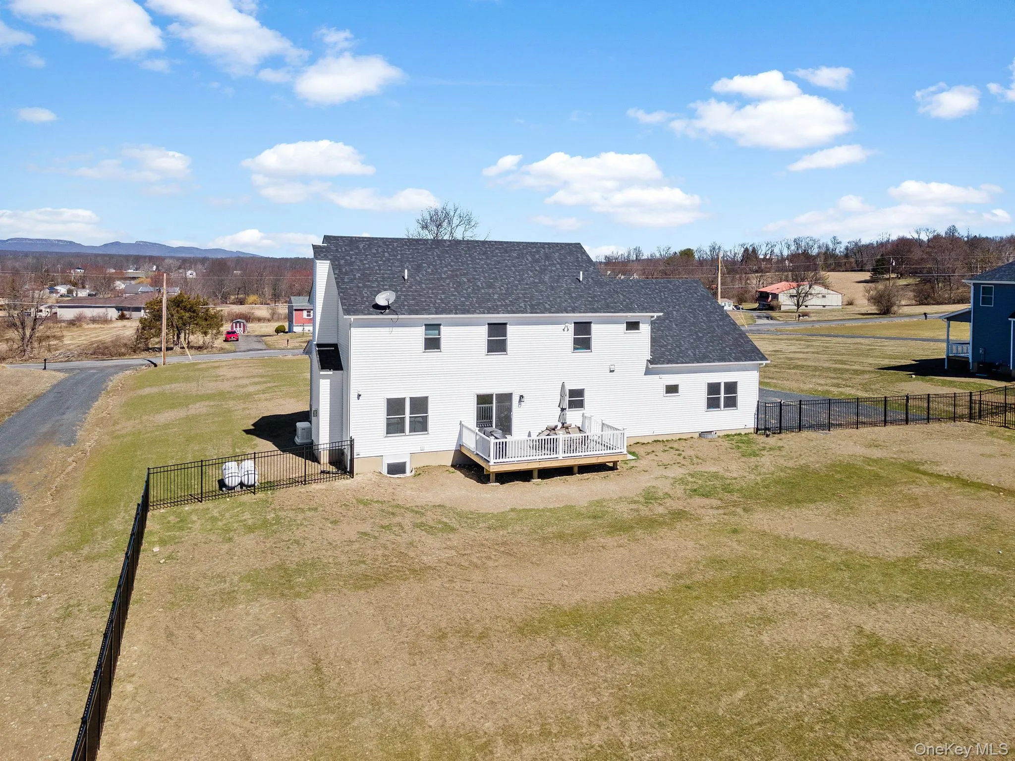 Back of property featuring a fenced backyard, a deck, a shingled roof, and a gate Back of property featuring a fenced backyard, a deck, a shingled roof, and a gate