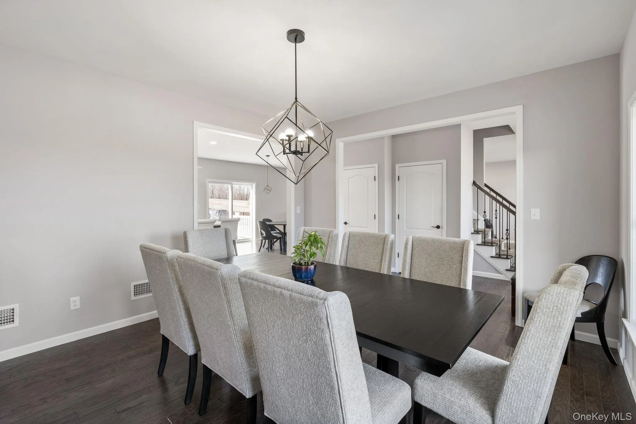 Dining space with stairway, dark wood-style floors, and a chandelier Dining space with stairway, dark wood-style floors, and a chandelier