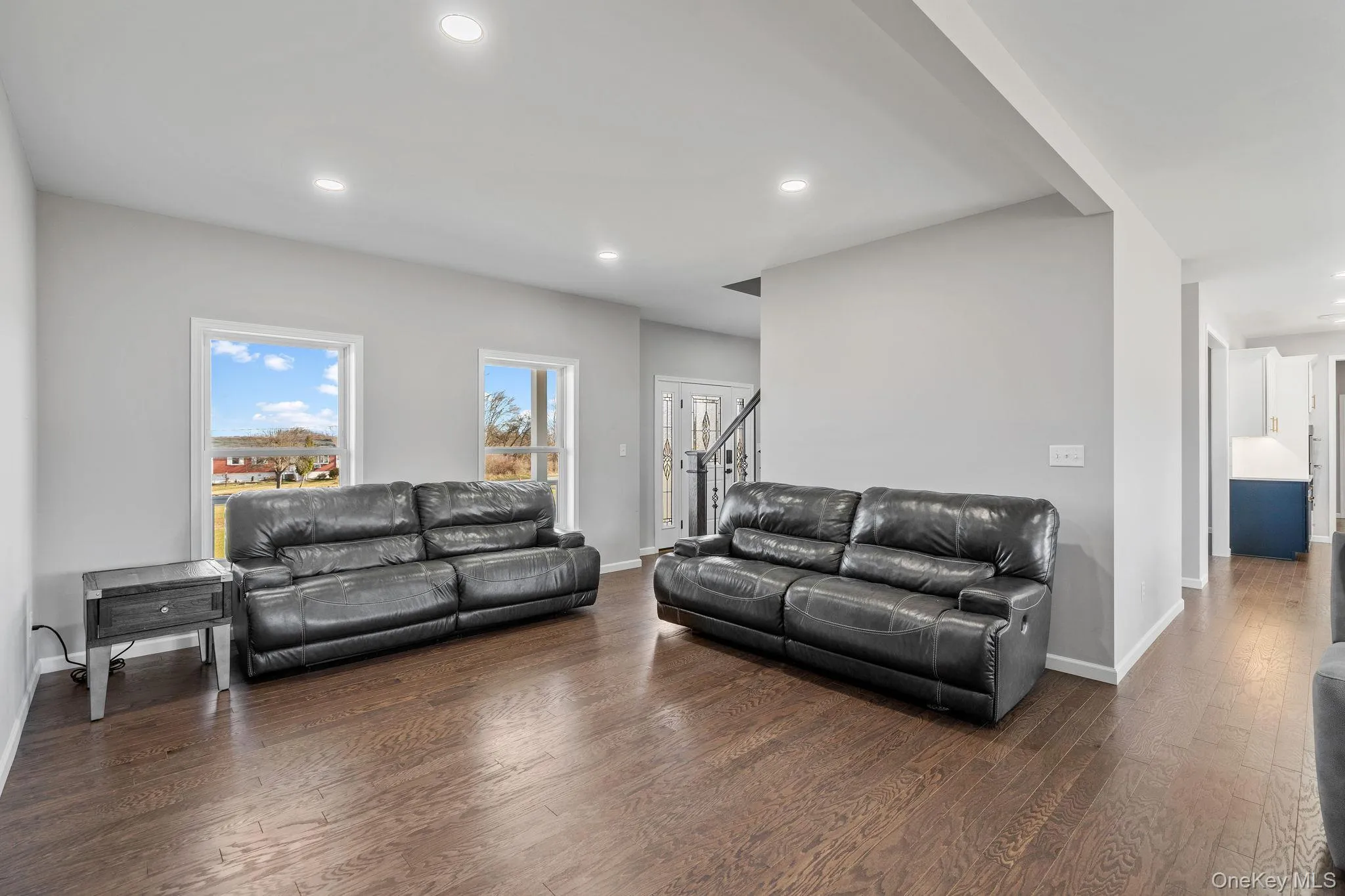 Living room featuring dark wood-style floors, recessed lighting, and stairway Living room featuring dark wood-style floors, recessed lighting, and stairway