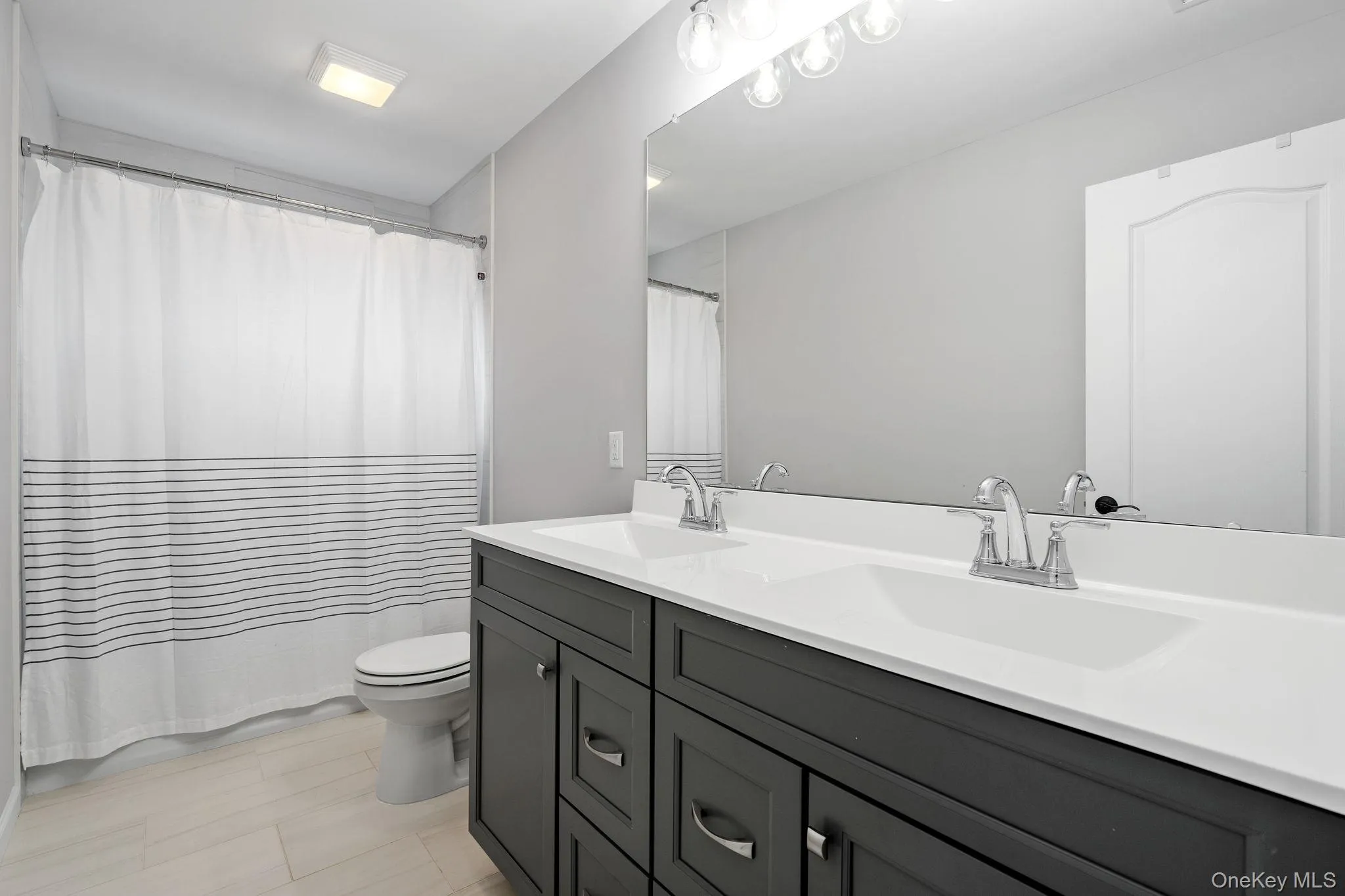 Full bathroom featuring double vanity and a shower with shower curtain Full bathroom featuring double vanity and a shower with shower curtain