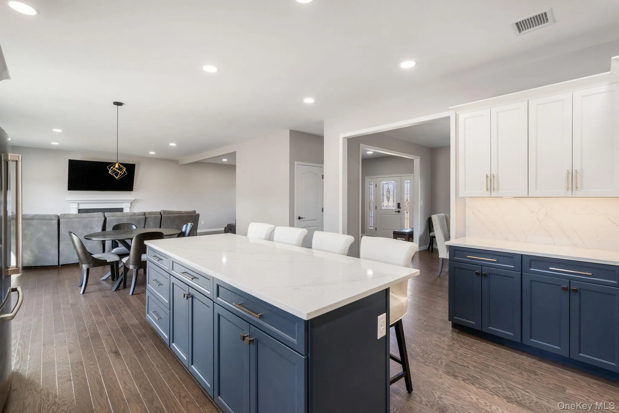Kitchen with blue cabinetry, a breakfast bar, light stone countertops, hanging light fixtures, and recessed lighting Kitchen with blue cabinetry, a breakfast bar, light stone countertops, hanging light fixtures, and recessed lighting