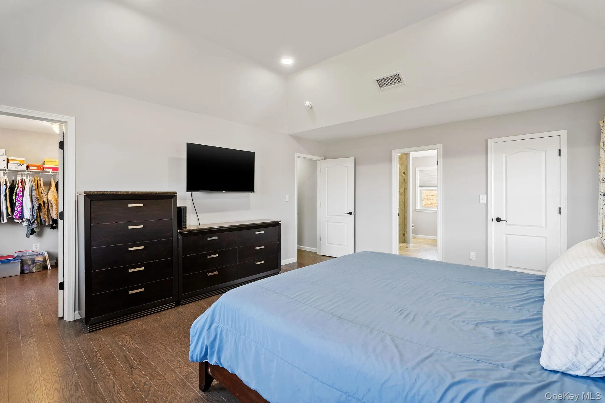 Bedroom featuring a spacious closet, dark wood-type flooring, ensuite bathroom, and recessed lighting Bedroom featuring a spacious closet, dark wood-type flooring, ensuite bathroom, and recessed lighting