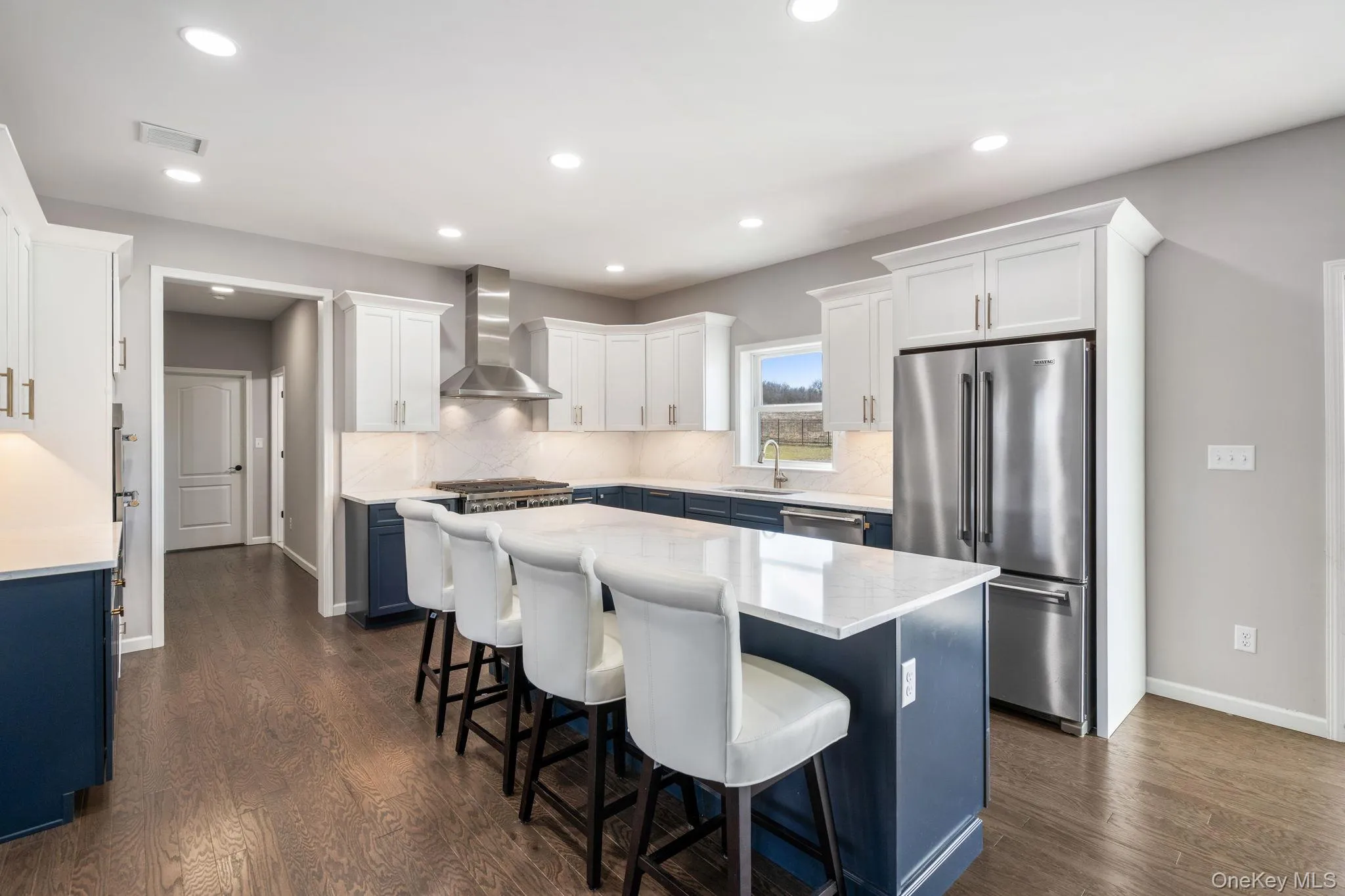 Kitchen featuring blue cabinetry, stainless steel appliances, white cabinets, a center island, and wall chimney exhaust hood Kitchen featuring blue cabinetry, stainless steel appliances, white cabinets, a center island, and wall chimney exhaust hood