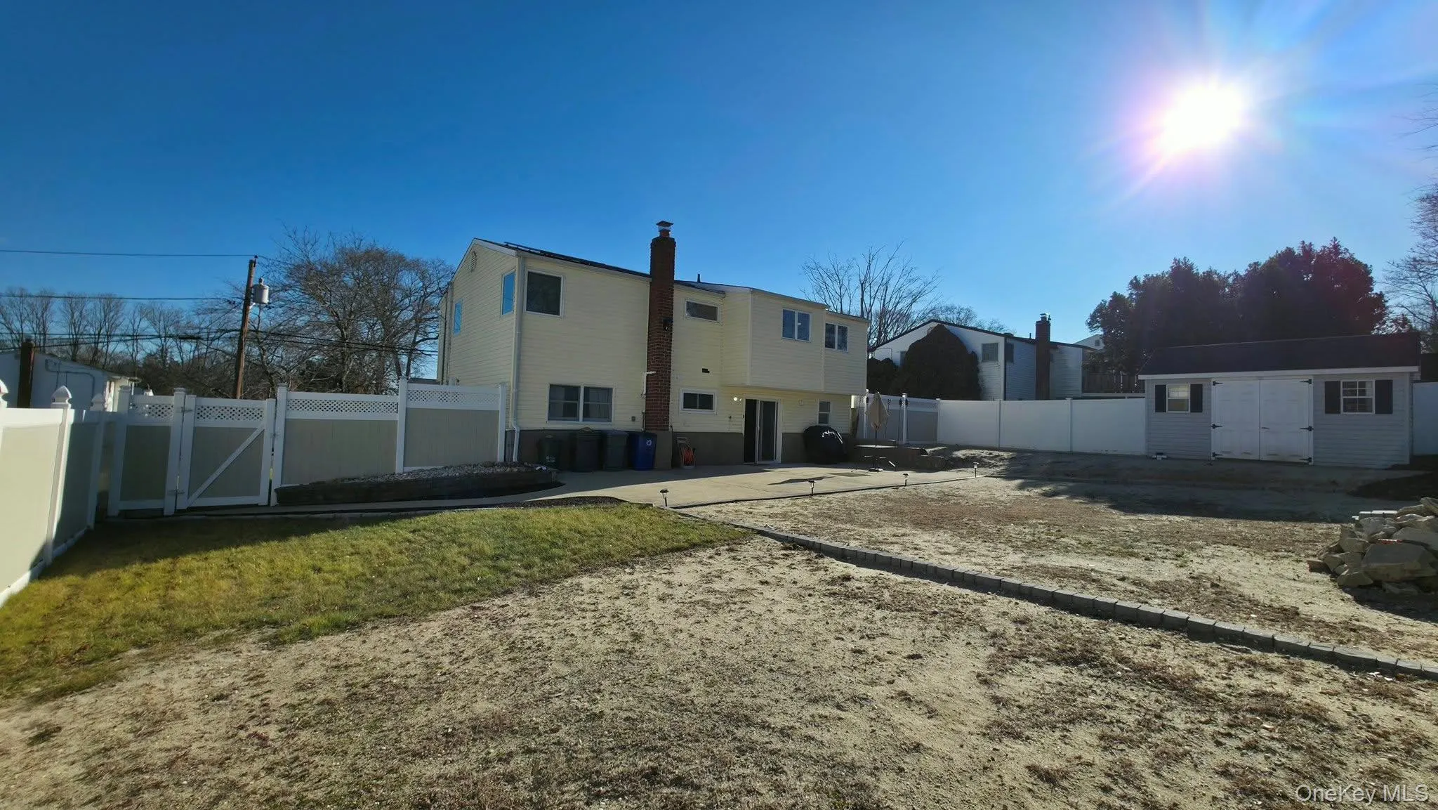 Rear view of property featuring a fenced backyard, a chimney, a gate, and a storage unit Rear view of property featuring a fenced backyard, a chimney, a gate, and a storage unit
