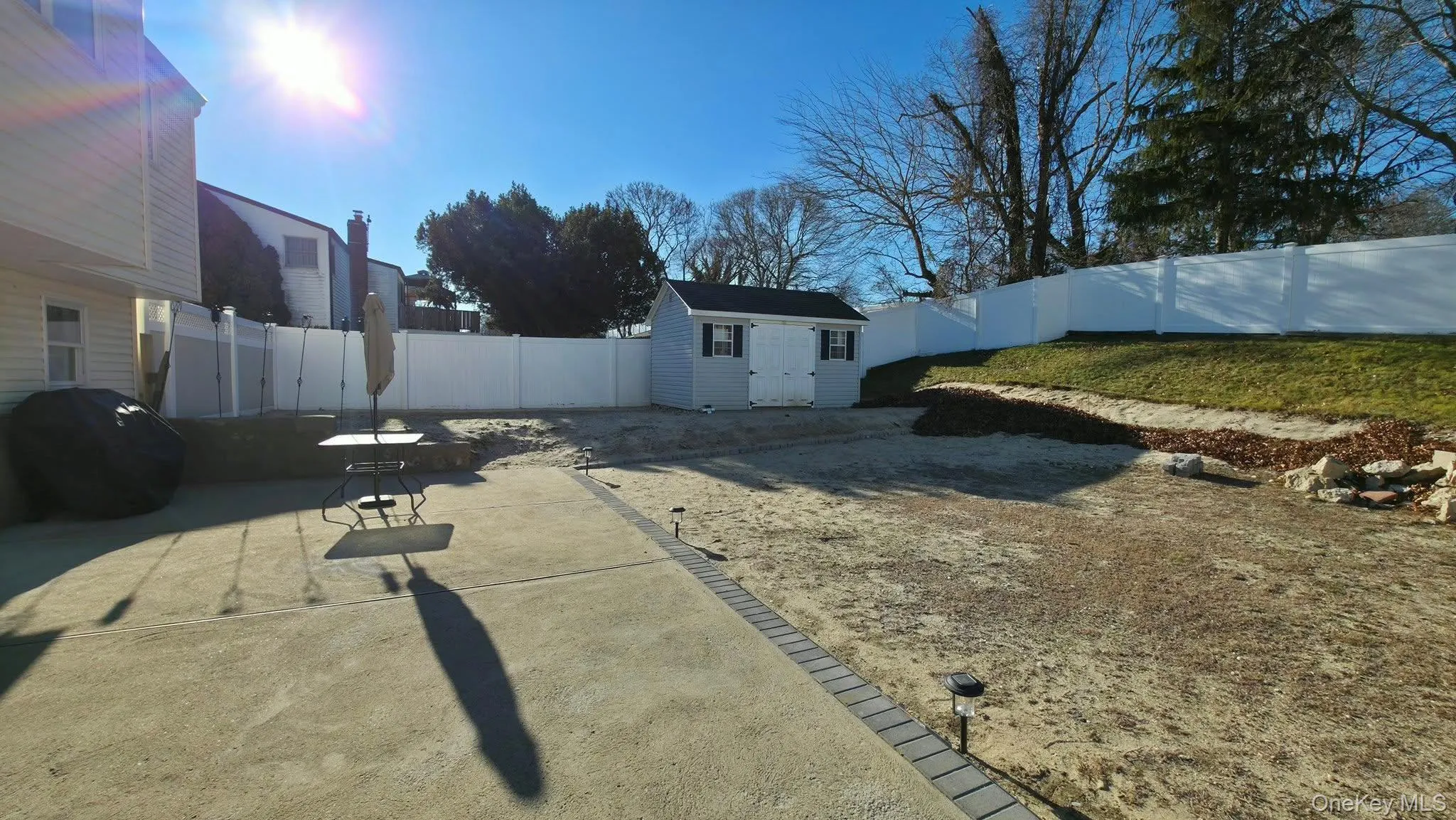 Fenced backyard with a storage unit and a patio area Fenced backyard with a storage unit and a patio area