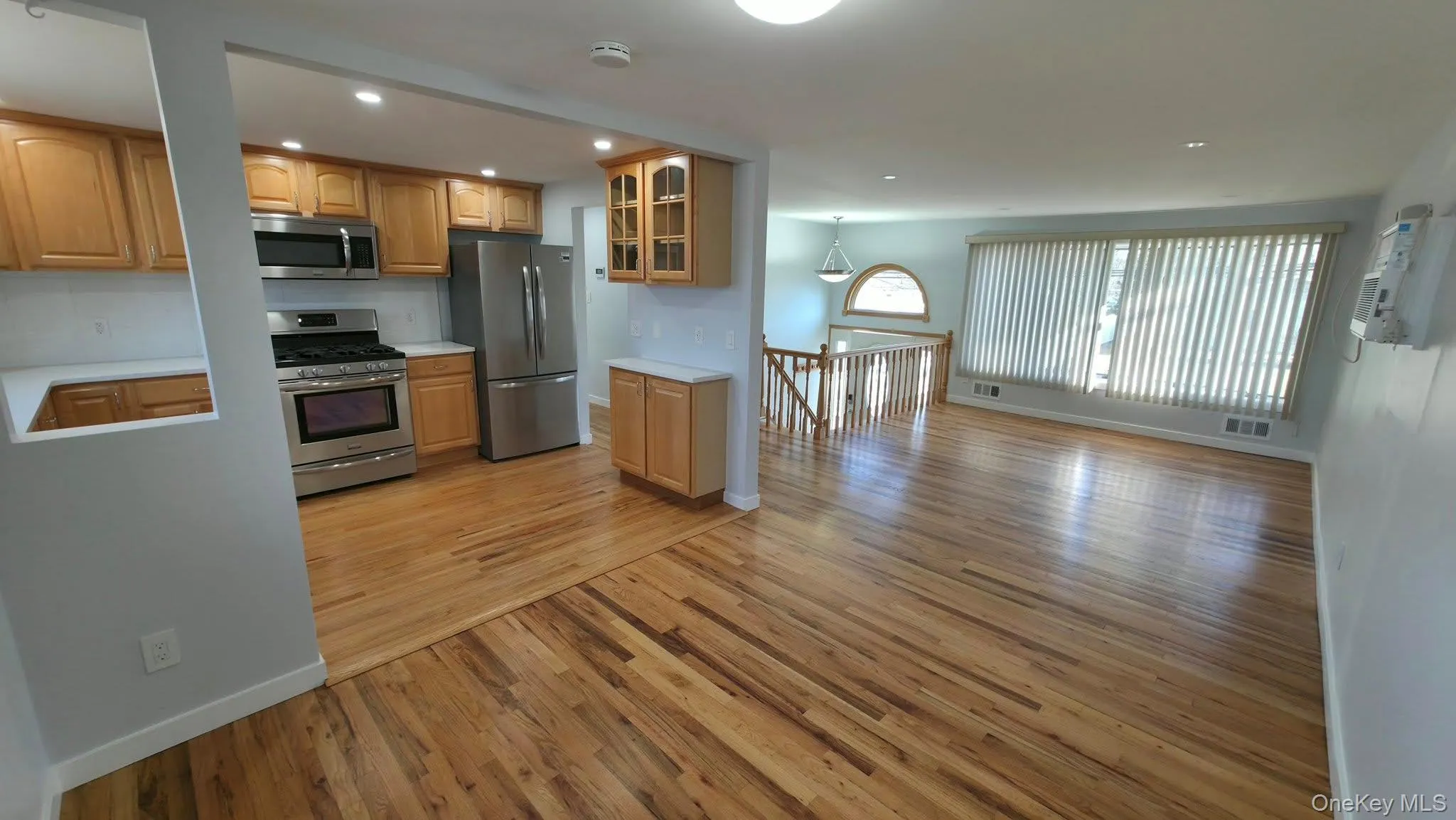 Kitchen with glass insert cabinets, light countertops, stainless steel appliances, light wood finished floors, and open floor plan Kitchen with glass insert cabinets, light countertops, stainless steel appliances, light wood finished floors, and open floor plan