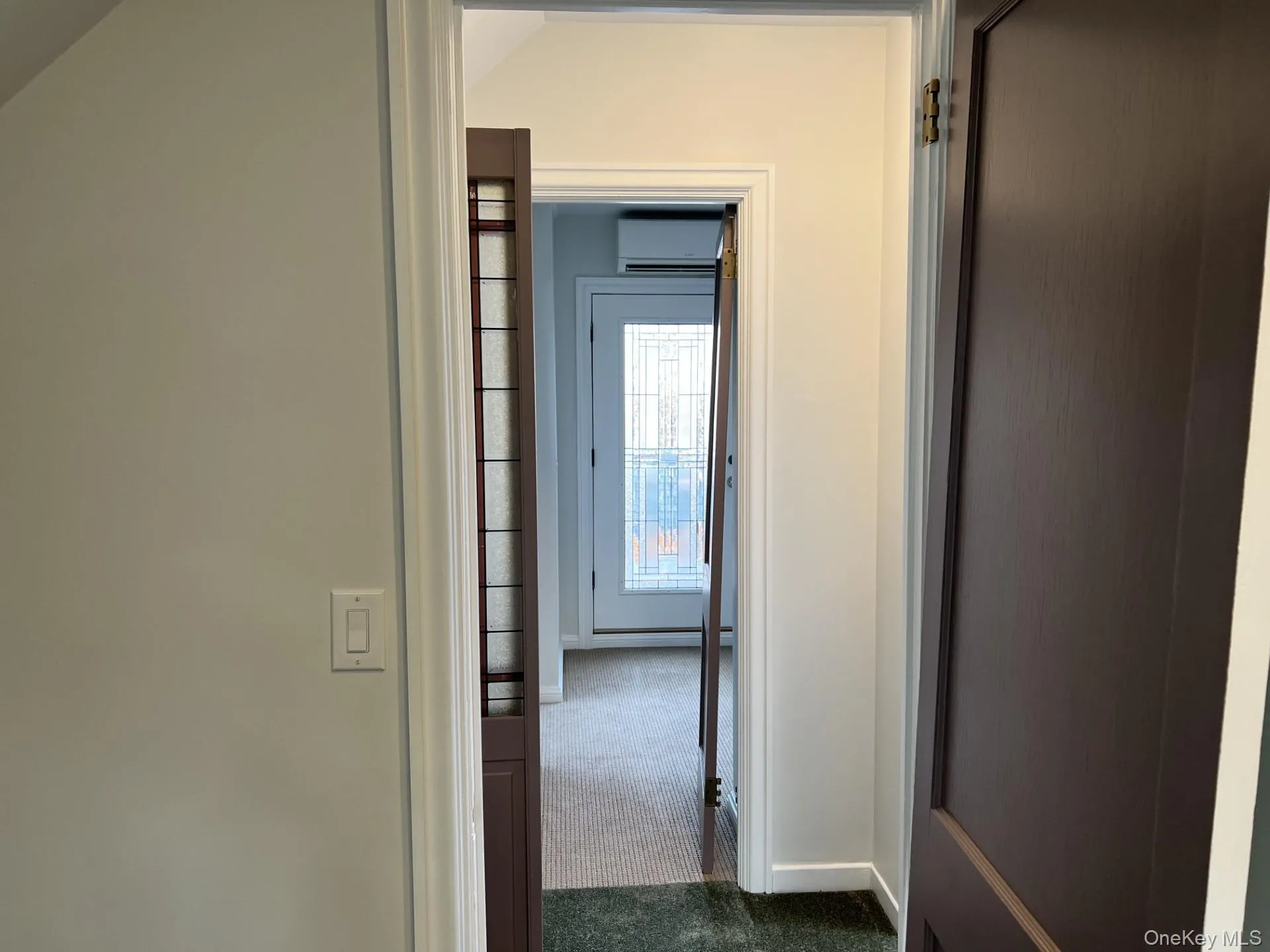 Hall with dark colored carpet, a wall mounted air conditioner, and lofted ceiling Hall with dark colored carpet, a wall mounted air conditioner, and lofted ceiling