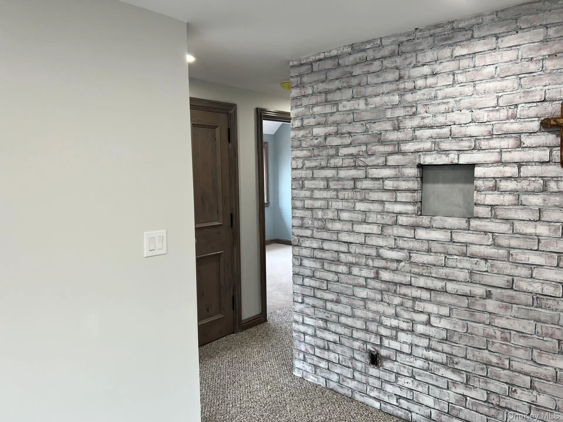 Hall with carpet flooring, brick wall, and recessed lighting Hall with carpet flooring, brick wall, and recessed lighting