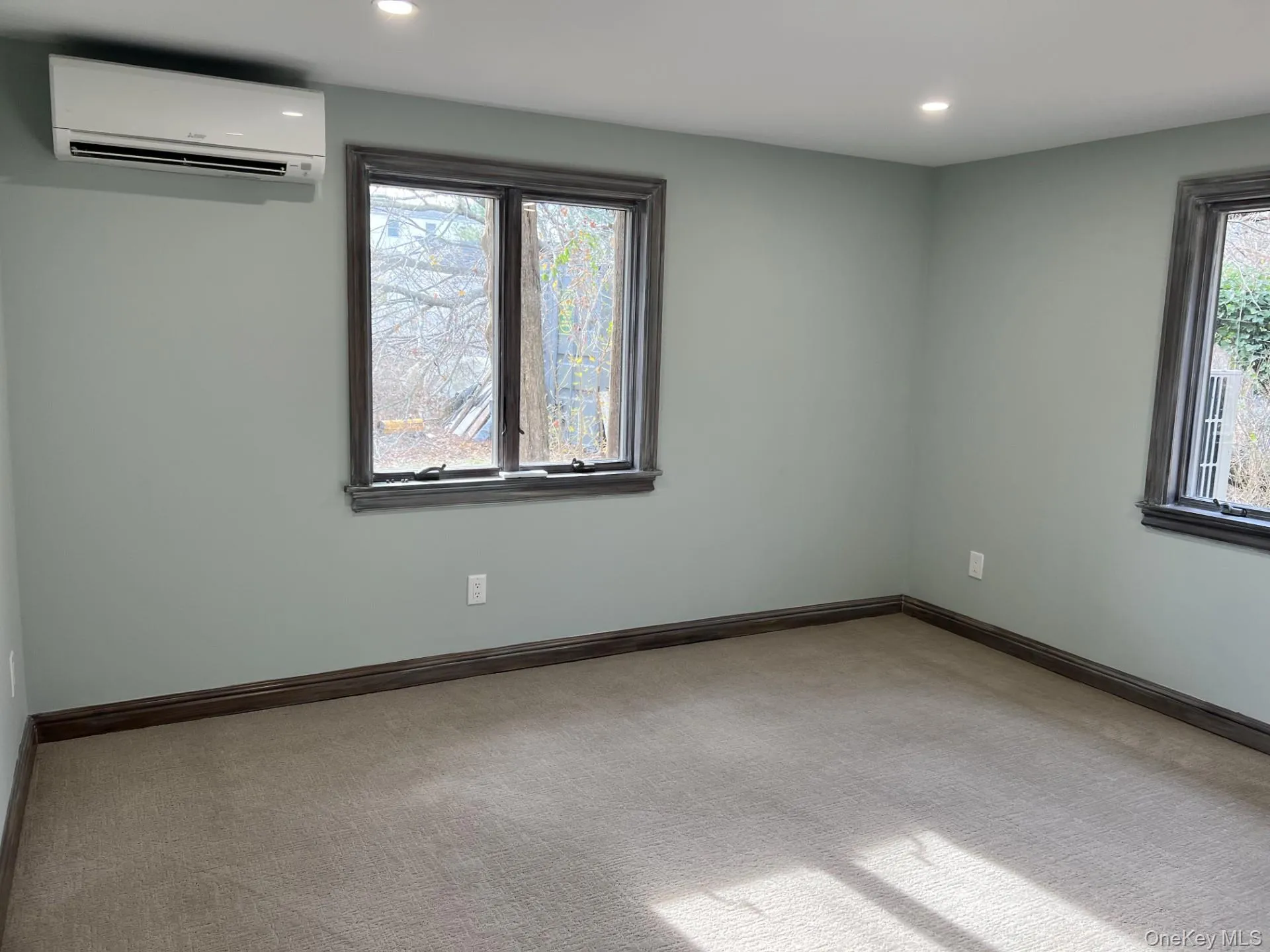Unfurnished room with light carpet, an AC wall unit, healthy amount of natural light, and recessed lighting Unfurnished room with light carpet, an AC wall unit, healthy amount of natural light, and recessed lighting