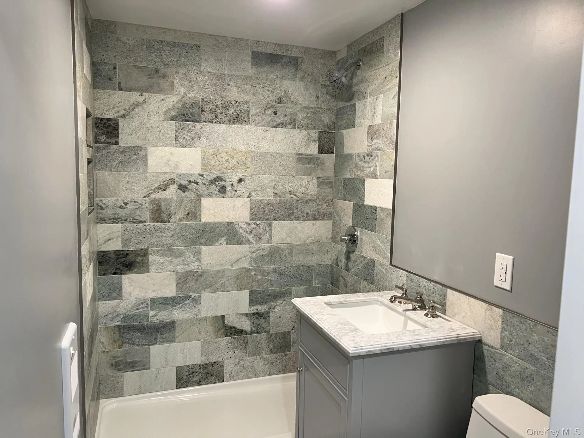 Bathroom with tile walls, vanity, a tile shower, and wainscoting Bathroom with tile walls, vanity, a tile shower, and wainscoting