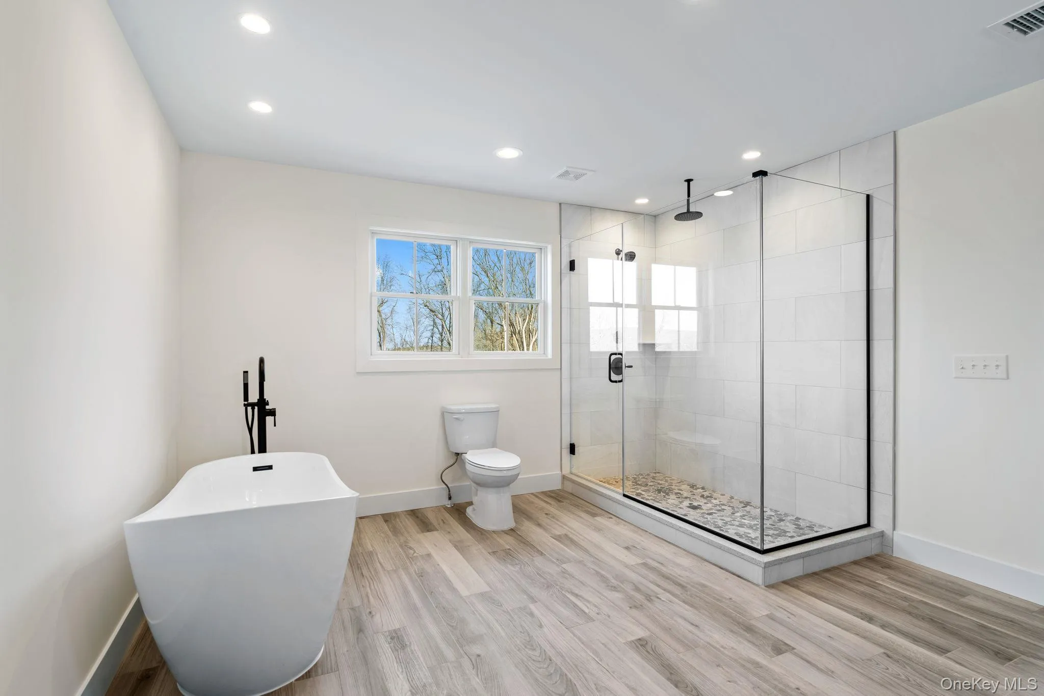 Bathroom featuring a soaking tub, a stall shower, light wood-style floors, and recessed lighting Bathroom featuring a soaking tub, a stall shower, light wood-style floors, and recessed lighting