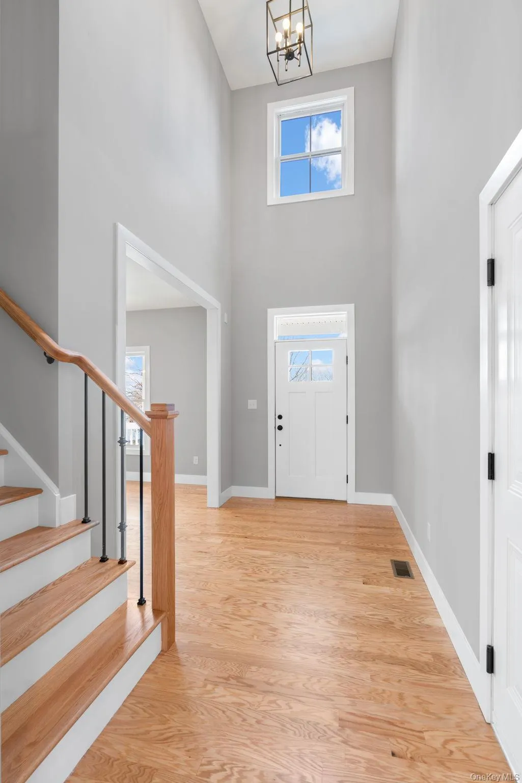 Entryway with a high ceiling, light wood-style flooring, stairs, and a chandelier Entryway with a high ceiling, light wood-style flooring, stairs, and a chandelier