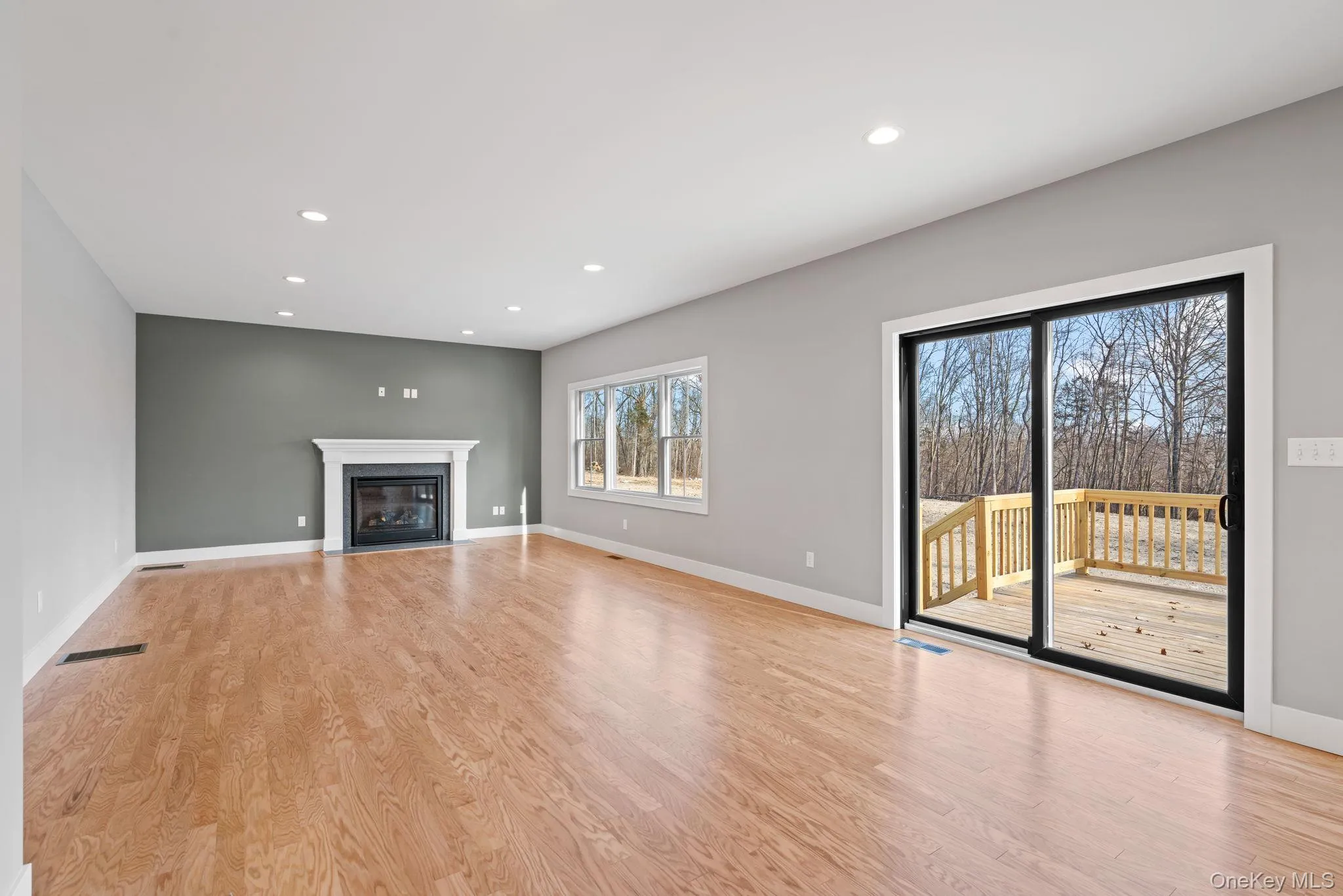 Unfurnished living room with recessed lighting, light wood-style floors, and a fireplace with flush hearth Unfurnished living room with recessed lighting, light wood-style floors, and a fireplace with flush hearth