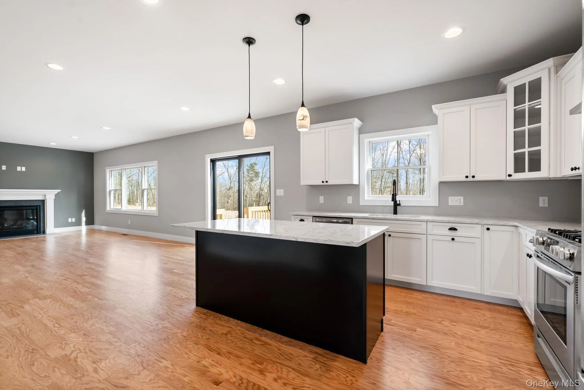 Kitchen with stainless steel range with gas stovetop, white cabinetry, hanging light fixtures, light wood-type flooring, and recessed lighting Kitchen with stainless steel range with gas stovetop, white cabinetry, hanging light fixtures, light wood-type flooring, and recessed lighting