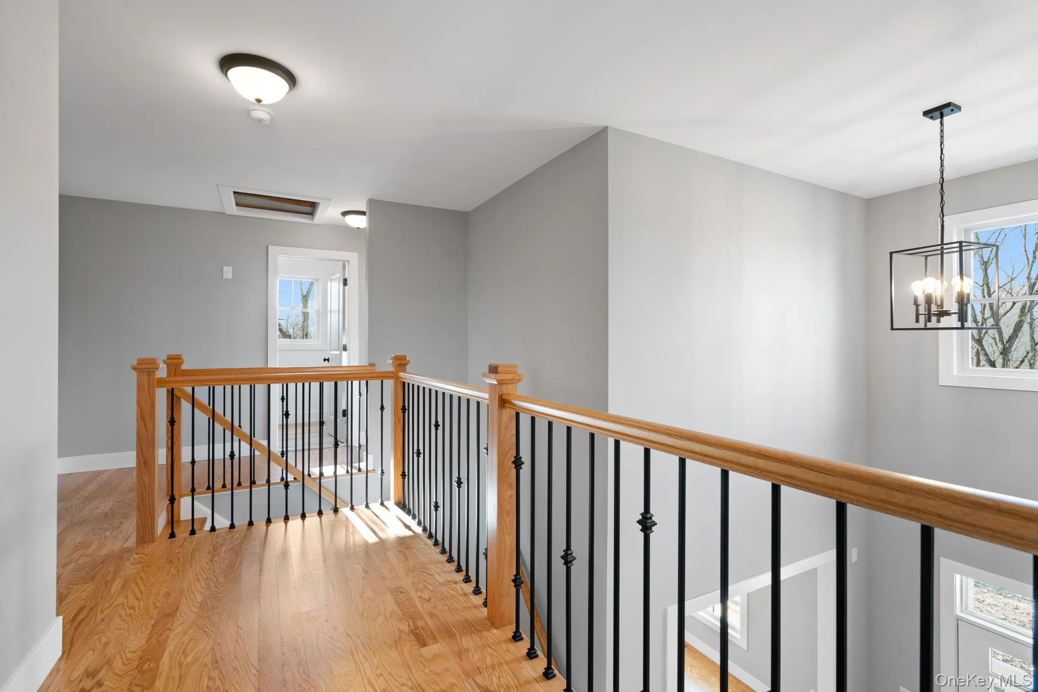 Corridor featuring an upstairs landing, light wood-style flooring, and attic access Corridor featuring an upstairs landing, light wood-style flooring, and attic access