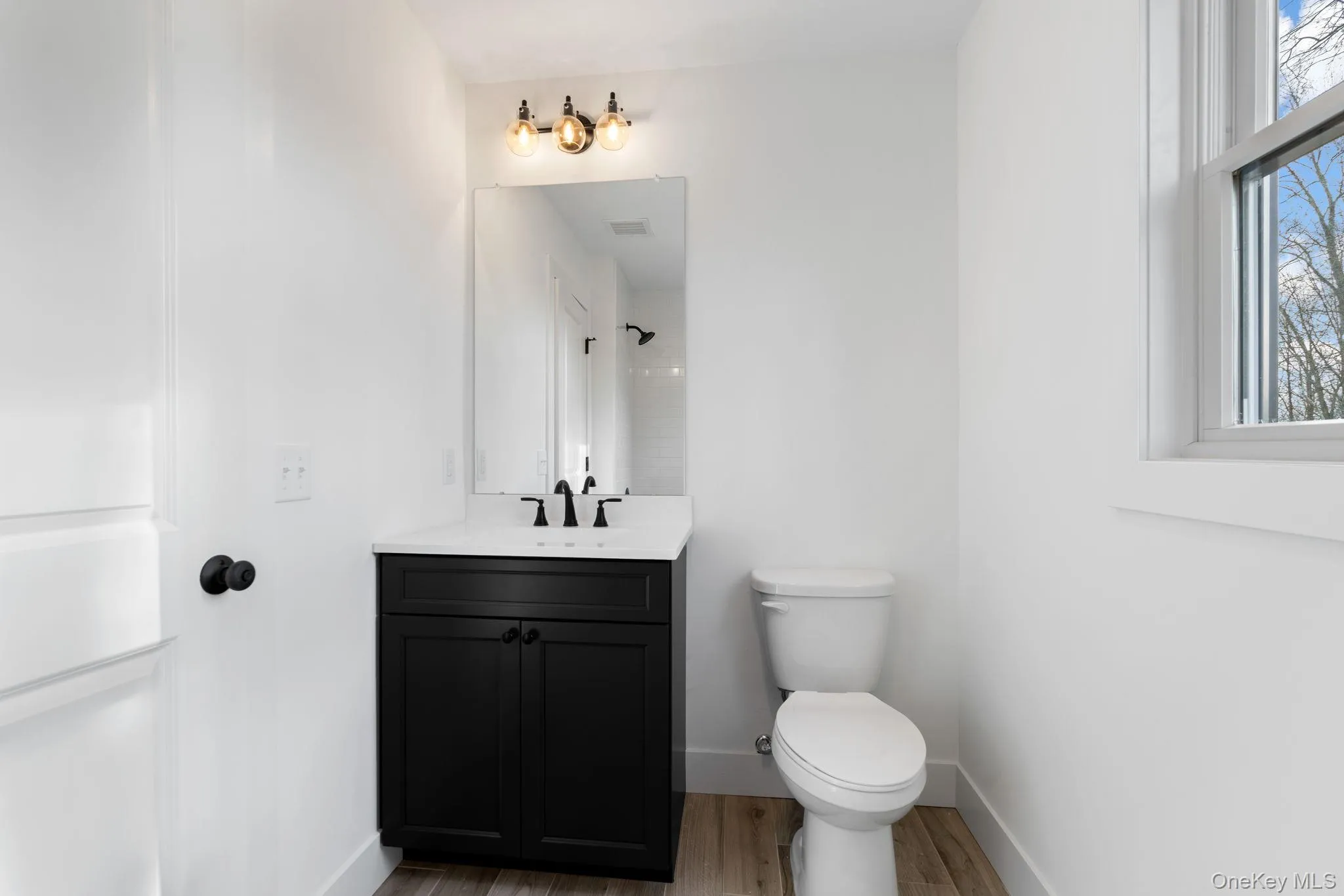 Full bathroom featuring vanity, a shower, and light wood-style floors Full bathroom featuring vanity, a shower, and light wood-style floors
