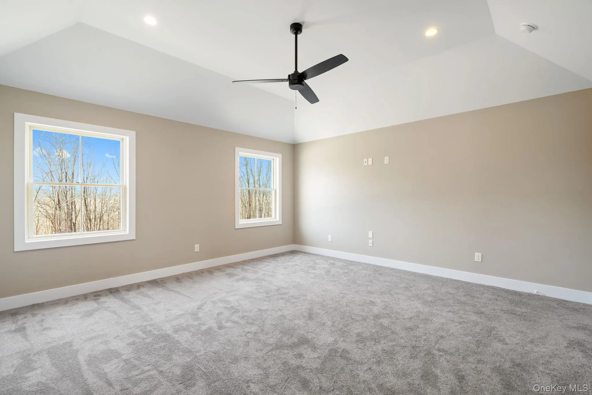 Carpeted spare room with vaulted ceiling and ceiling fan Carpeted spare room with vaulted ceiling and ceiling fan