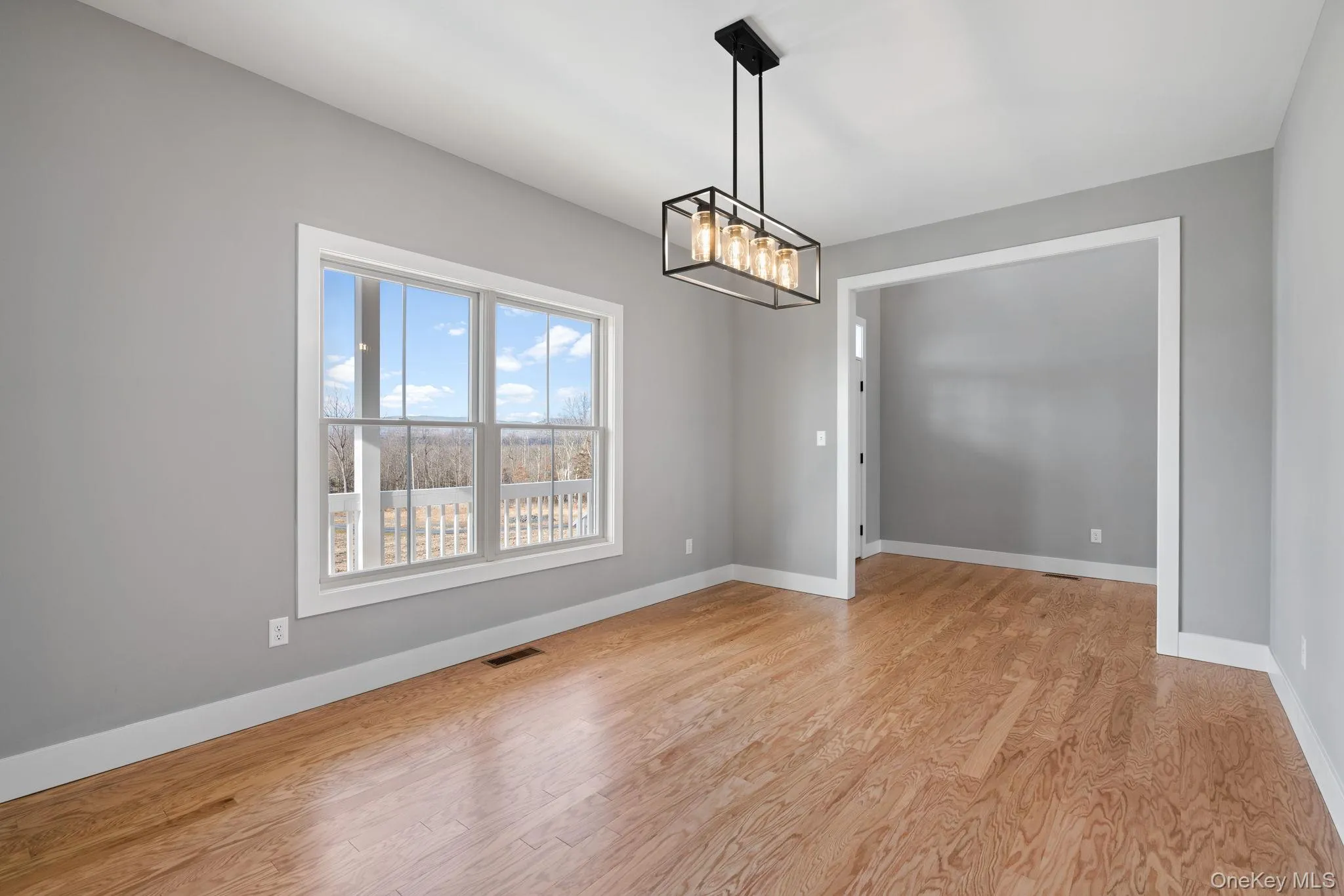 Spare room featuring light wood-style flooring and a chandelier Spare room featuring light wood-style flooring and a chandelier