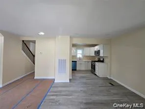 Unfurnished living room featuring stairs and wood finished floors Unfurnished living room featuring stairs and wood finished floors