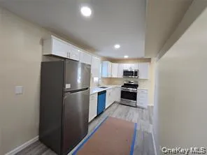 Kitchen with white cabinets, stainless steel appliances, light countertops, light wood-style flooring, and recessed lighting Kitchen with white cabinets, stainless steel appliances, light countertops, light wood-style flooring, and recessed lighting