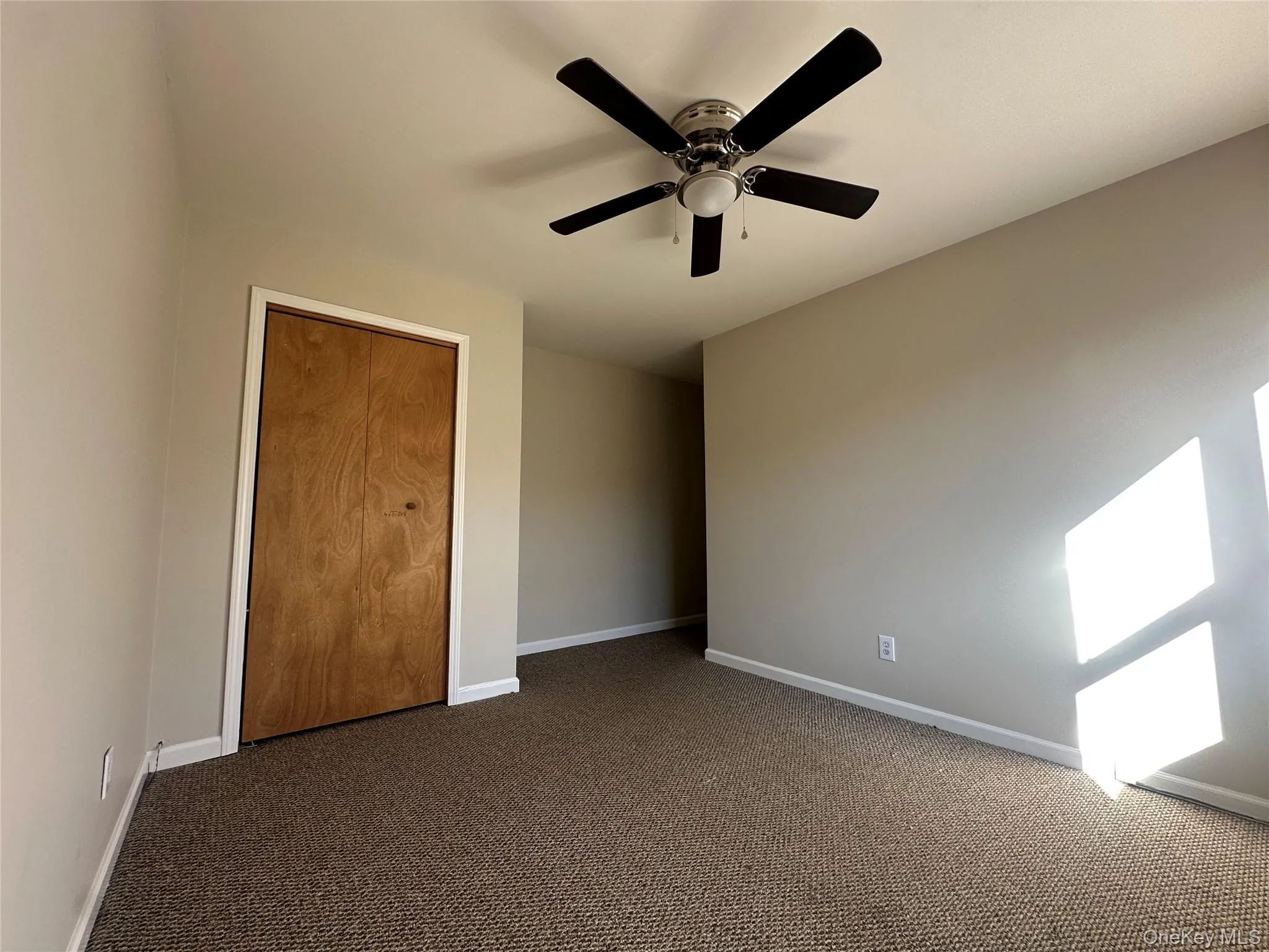 Unfurnished bedroom with carpet floors, a ceiling fan, and a closet Unfurnished bedroom with carpet floors, a ceiling fan, and a closet