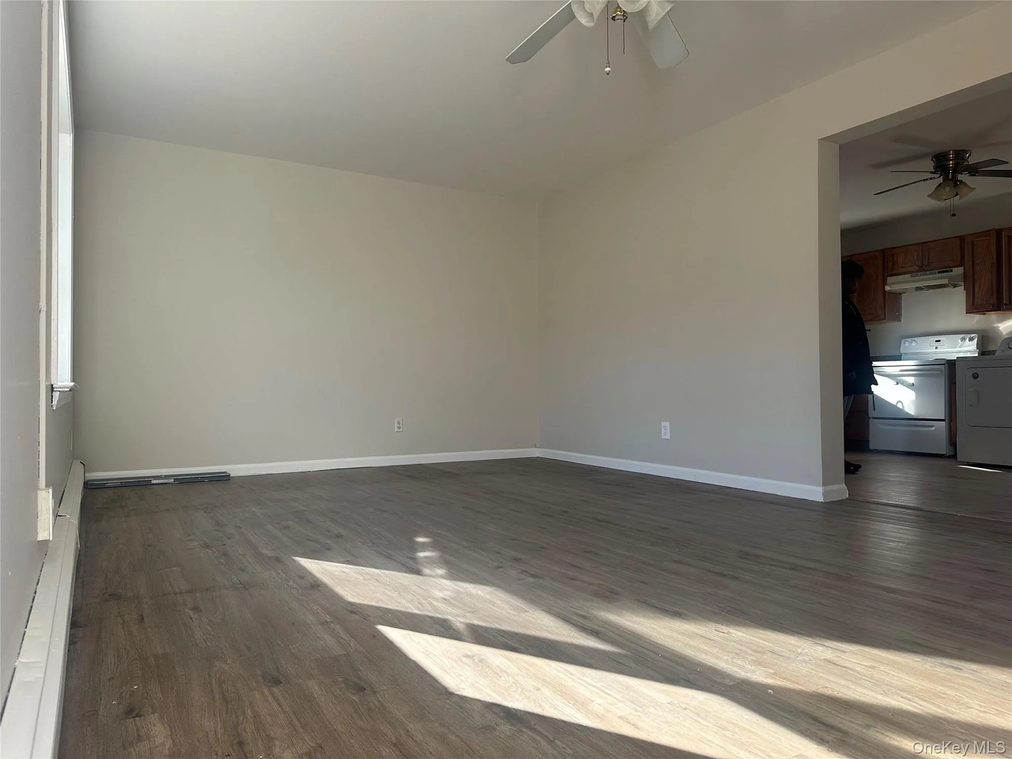 Spare room featuring baseboard heating, dark wood-type flooring, and ceiling fan Spare room featuring baseboard heating, dark wood-type flooring, and ceiling fan
