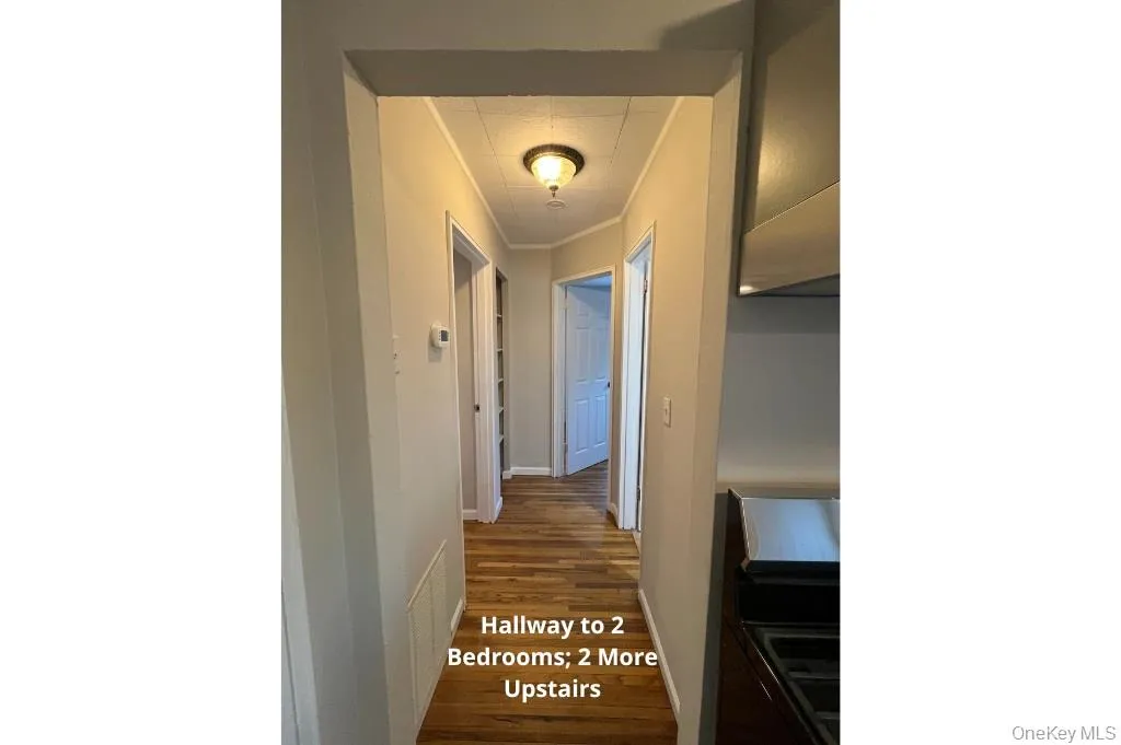 Corridor with ornamental molding and dark wood-style flooring Corridor with ornamental molding and dark wood-style flooring