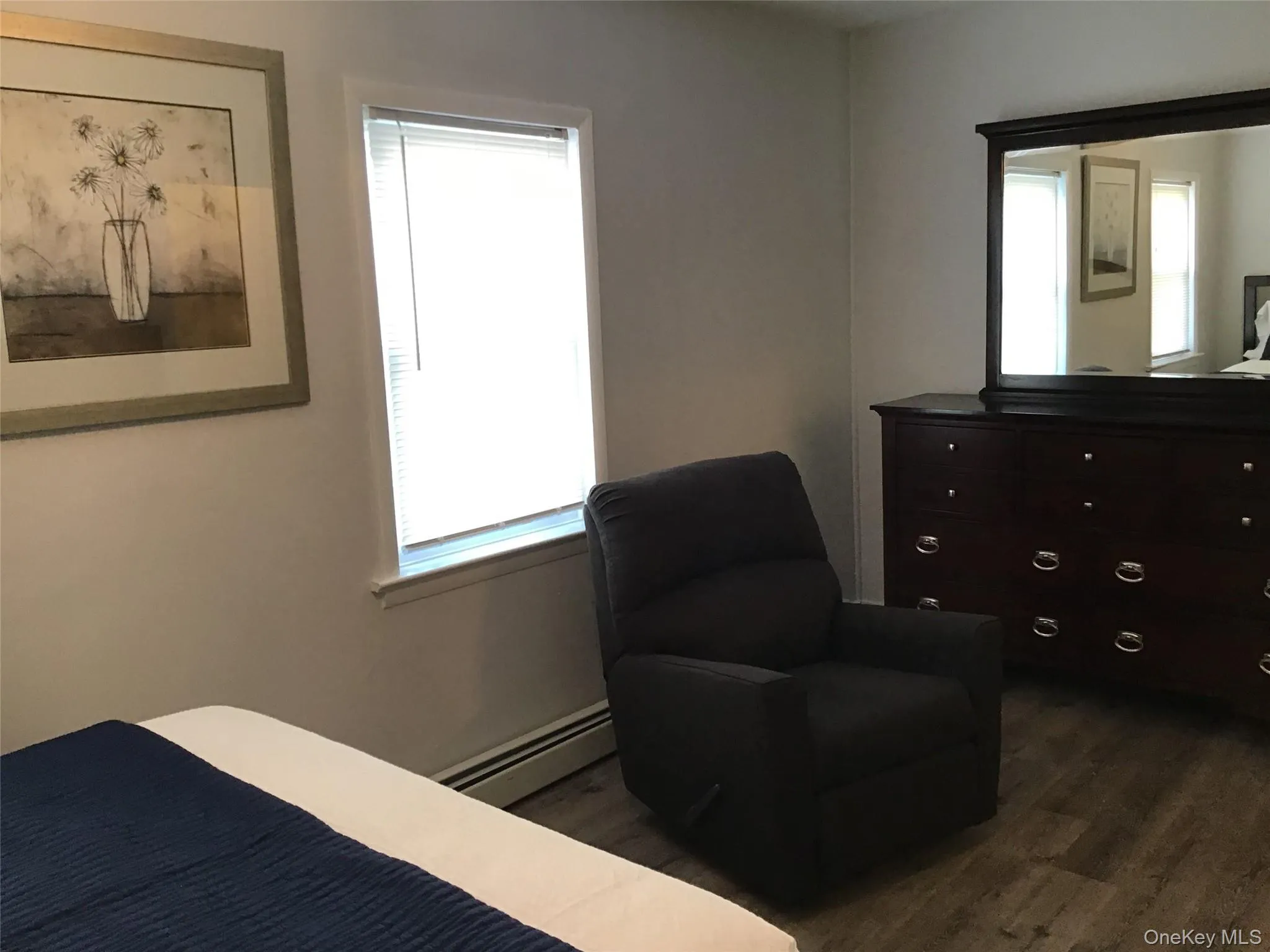 Bedroom featuring baseboard heating and dark wood finished floors Bedroom featuring baseboard heating and dark wood finished floors