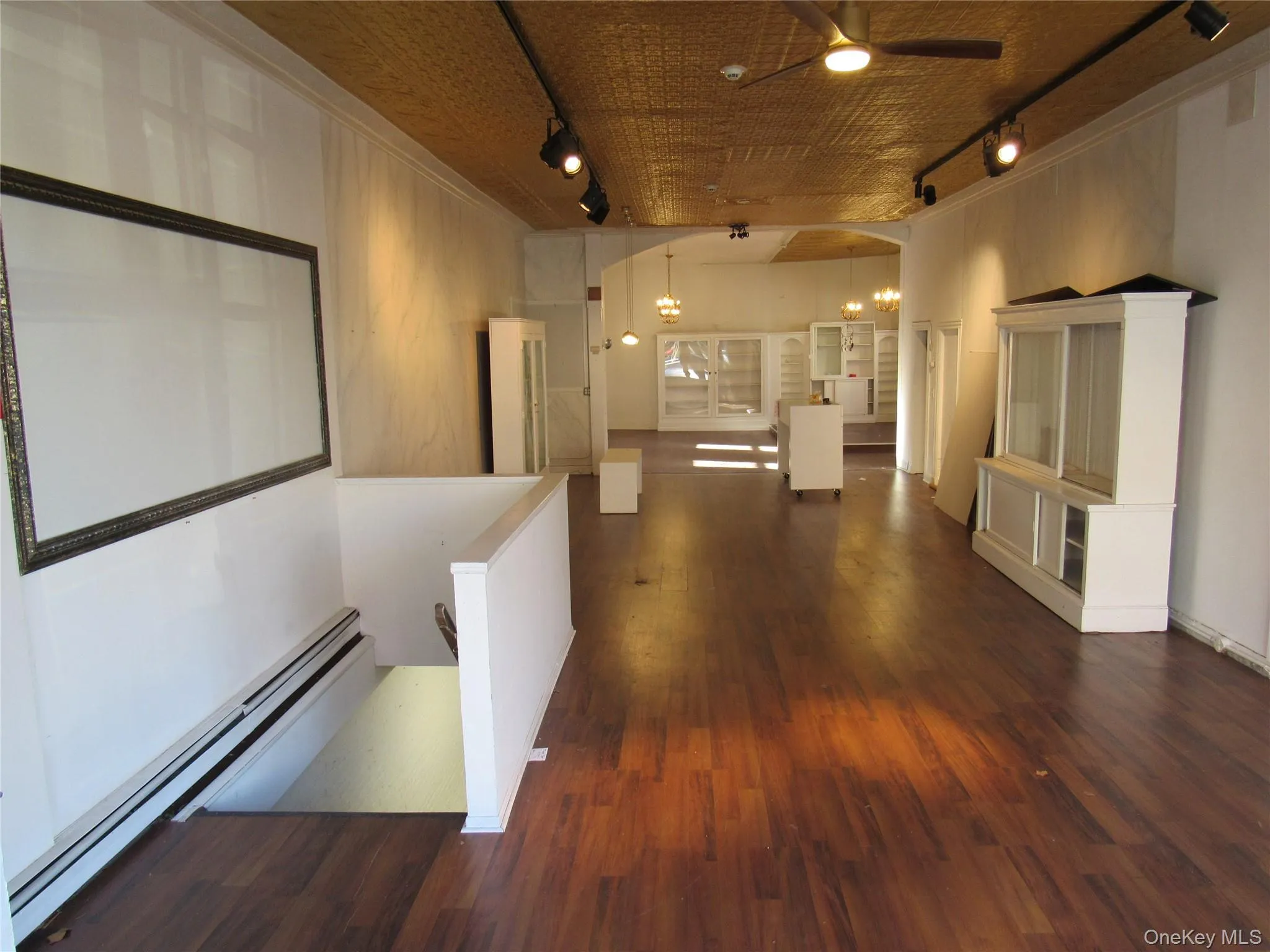 Corridor featuring track lighting, a baseboard radiator, dark wood-style flooring, a chandelier, Corridor featuring track lighting, a baseboard radiator, dark wood-style flooring, a chandelier,