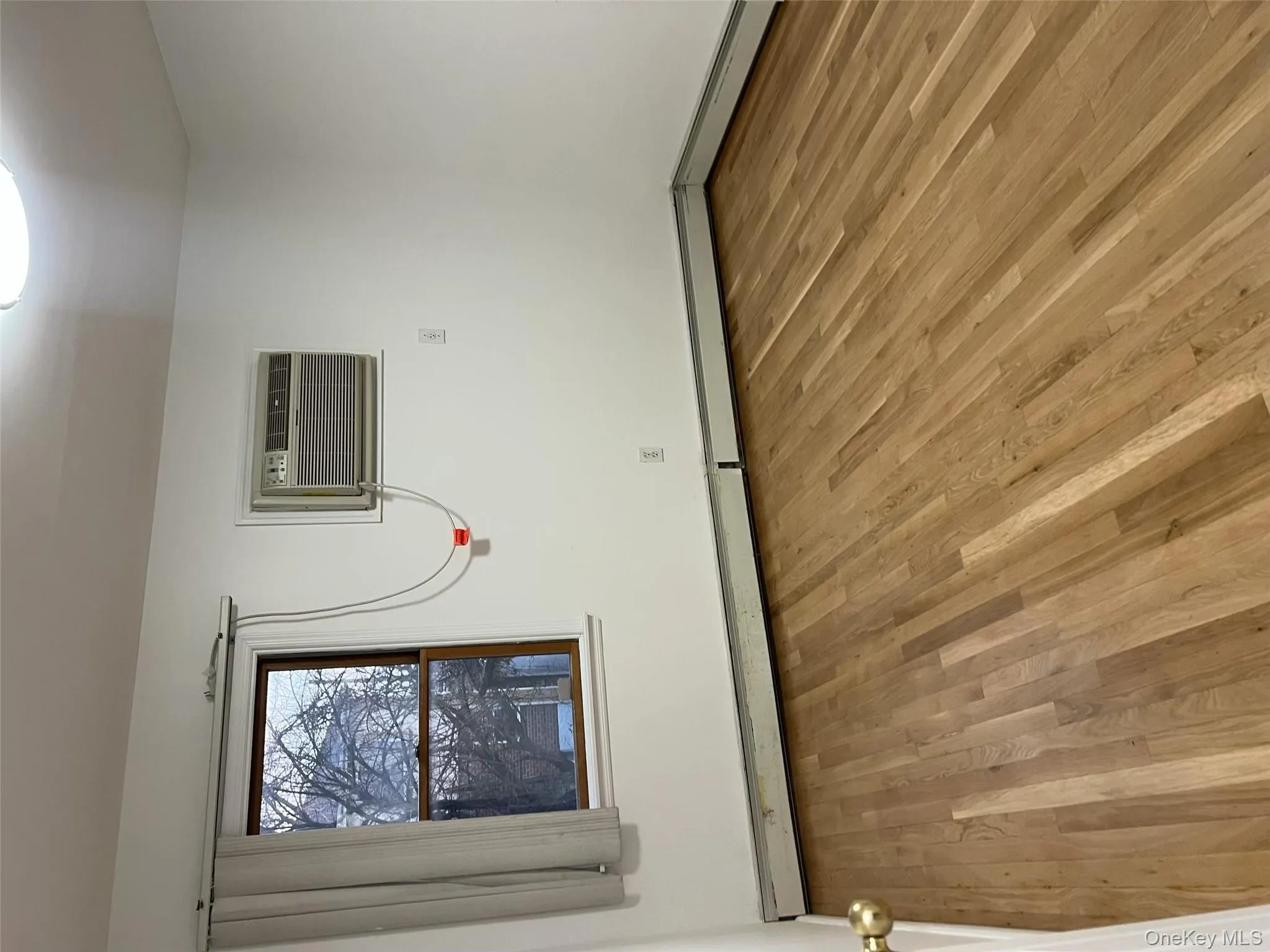 Unfurnished room with light wood-style flooring, baseboard heating, and an AC wall unit Unfurnished room with light wood-style flooring, baseboard heating, and an AC wall unit