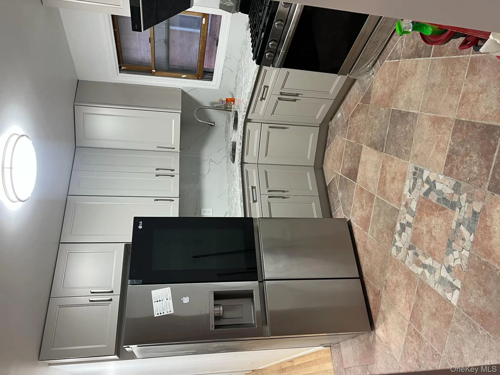 Kitchen with black fridge, range, light stone counters, decorative backsplash, and ventilation hood Kitchen with black fridge, range, light stone counters, decorative backsplash, and ventilation hood