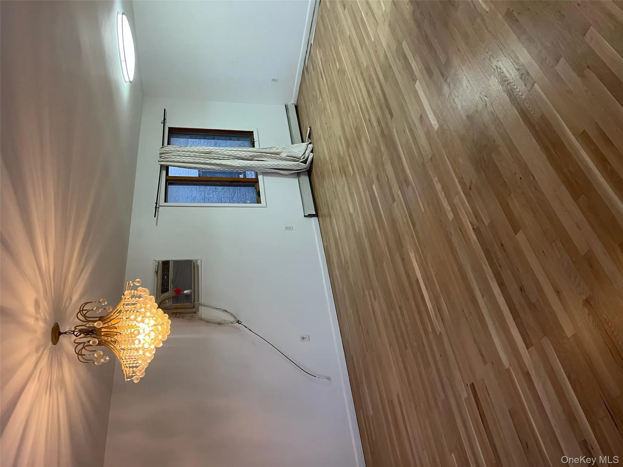 Unfurnished room featuring light wood-style floors, a chandelier, and a wall unit AC Unfurnished room featuring light wood-style floors, a chandelier, and a wall unit AC