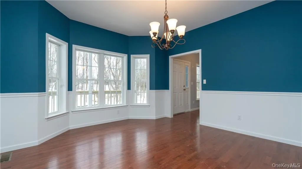 Unfurnished dining area featuring a chandelier and dark wood-style floors Unfurnished dining area featuring a chandelier and dark wood-style floors