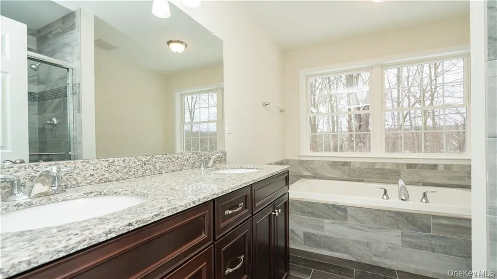 Full bath featuring a garden tub, double vanity, and a shower stall Full bath featuring a garden tub, double vanity, and a shower stall