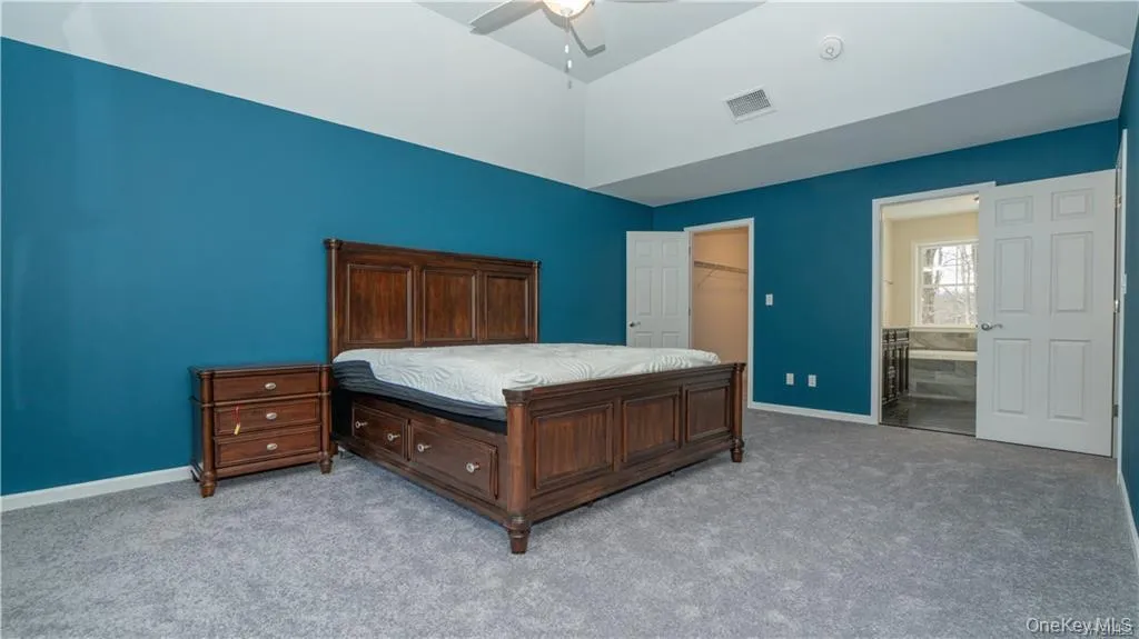 Carpeted bedroom with a walk in closet, a ceiling fan, and lofted ceiling Carpeted bedroom with a walk in closet, a ceiling fan, and lofted ceiling