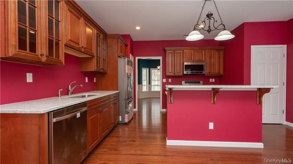 Kitchen featuring brown cabinets, a kitchen bar, appliances with stainless steel finishes, pendant lighting, and recessed lighting Kitchen featuring brown cabinets, a kitchen bar, appliances with stainless steel finishes, pendant lighting, and recessed lighting