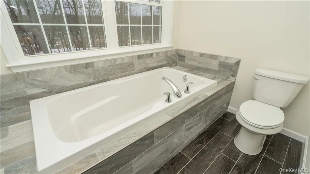 Bathroom featuring a bath and baseboards Bathroom featuring a bath and baseboards